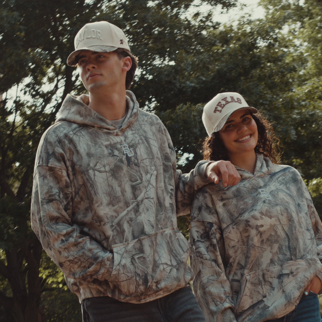 Texas camo hat close-up worn outdoors, tan TEXAS embroidery catching the light
