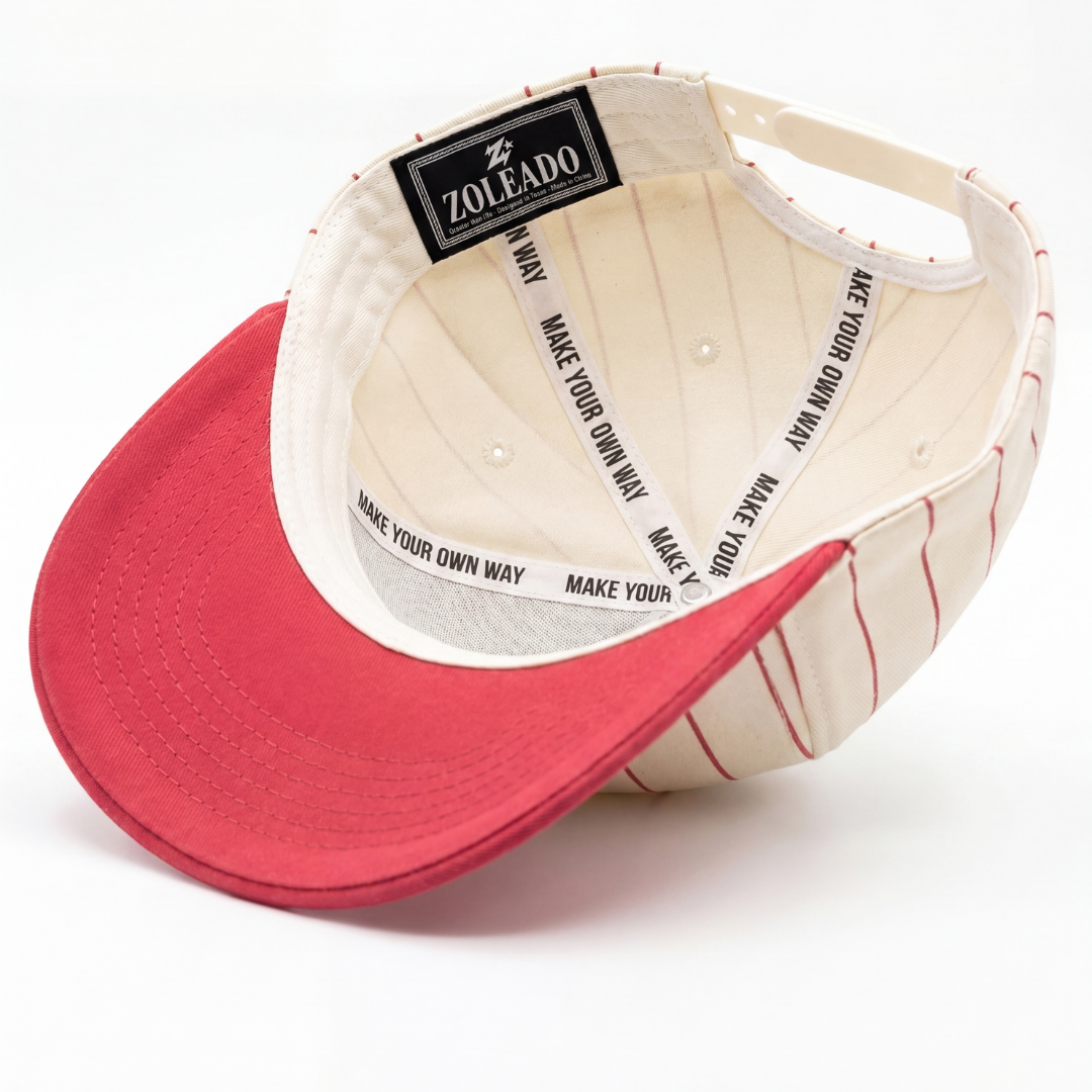 Born in the USA hat detail — close-up of navy 3D embroidered USA lettering on red pinstripe twill