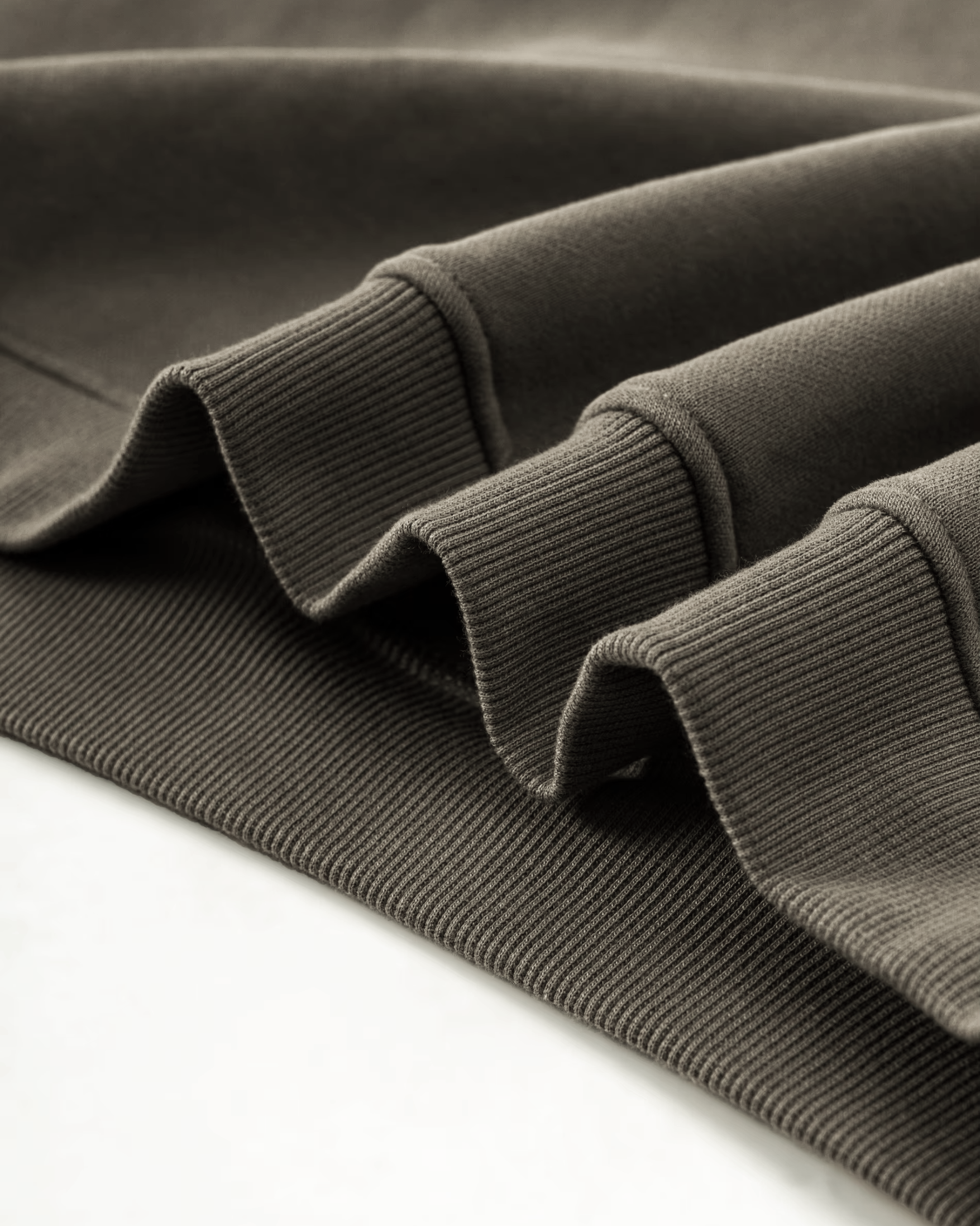 Close-up of a folded olive green hoodie fabric on a white background