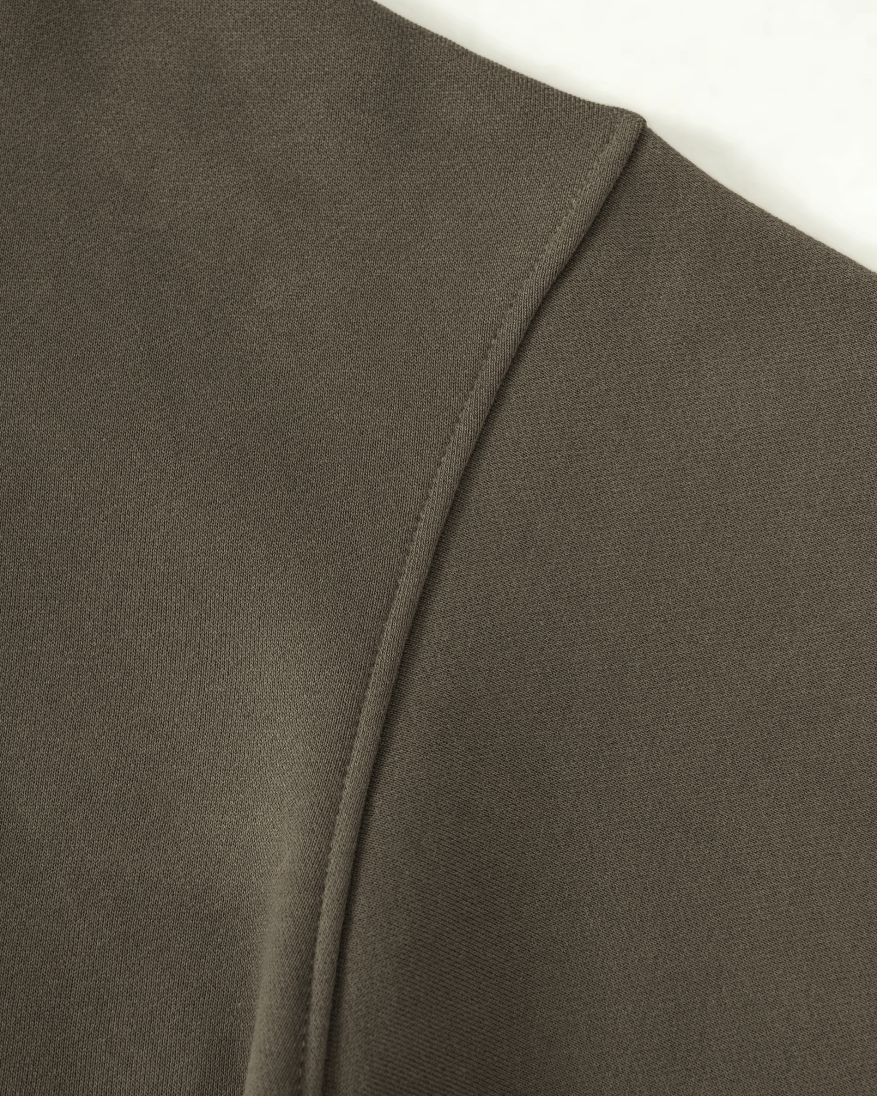 Close-up of an olive green hoodie fabric with a visible seam on a white background