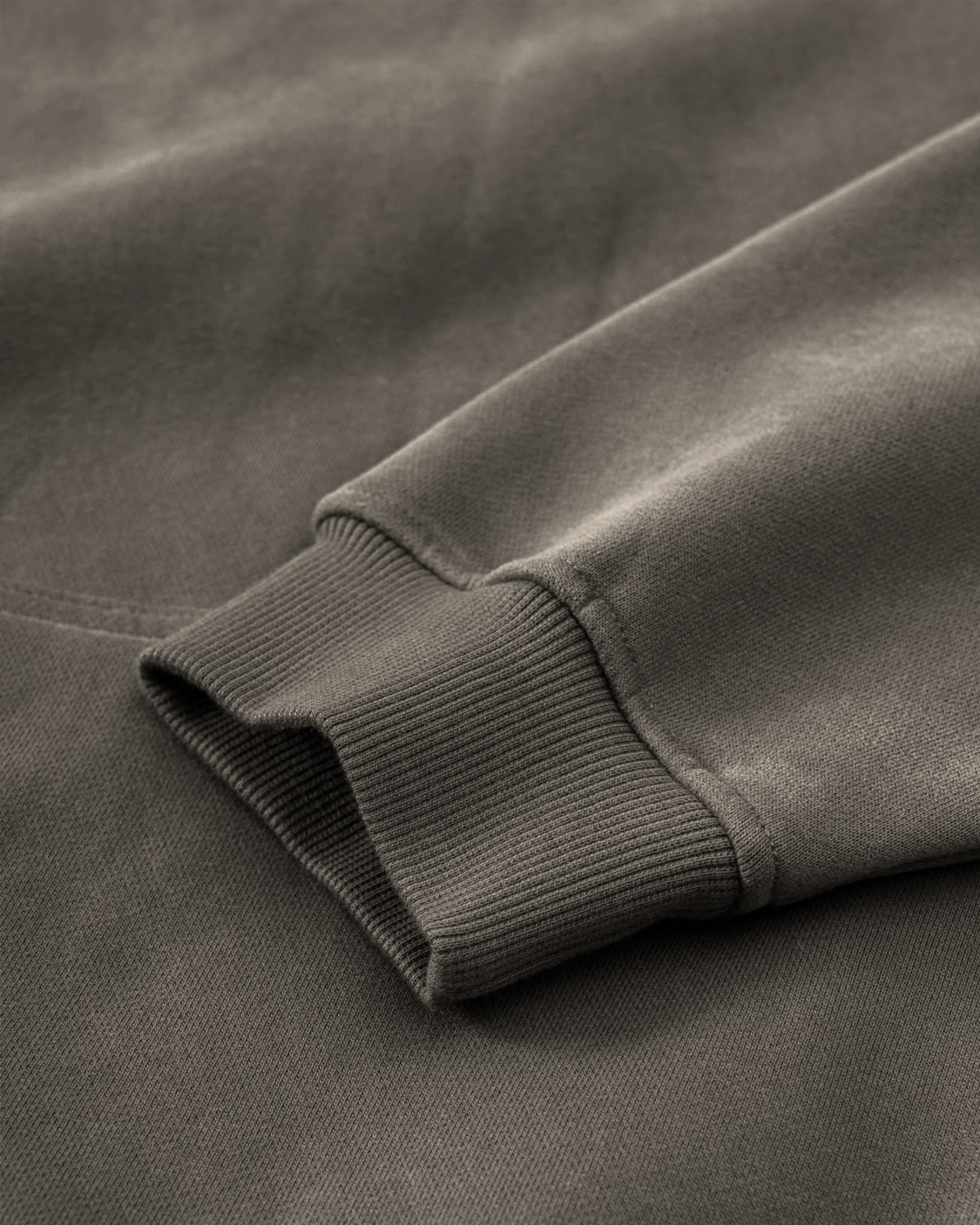 Close-up of an olive green hoodie fabric with a ribbed edge