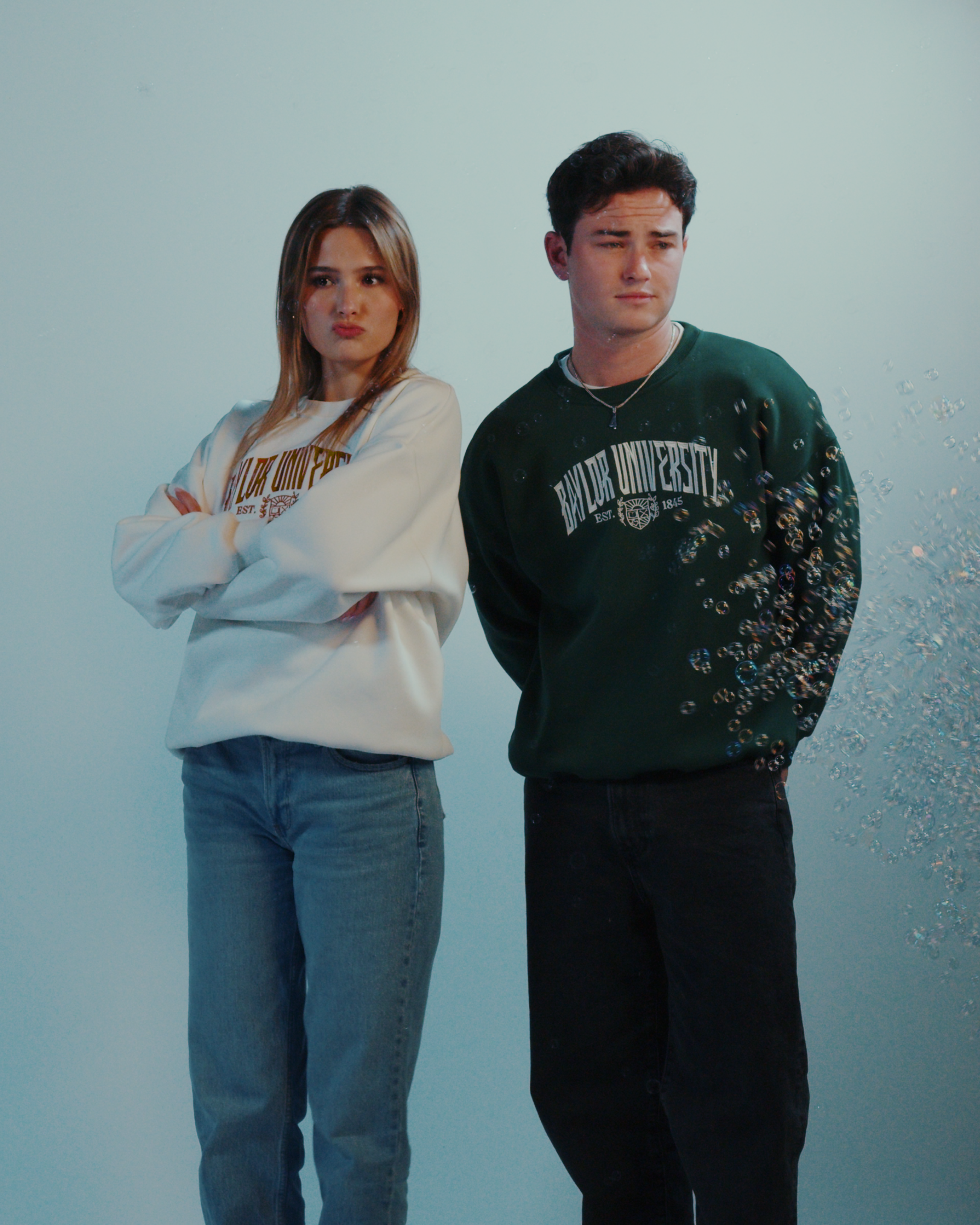 Two people wearing Baylor University sweatshirts against a light blue background