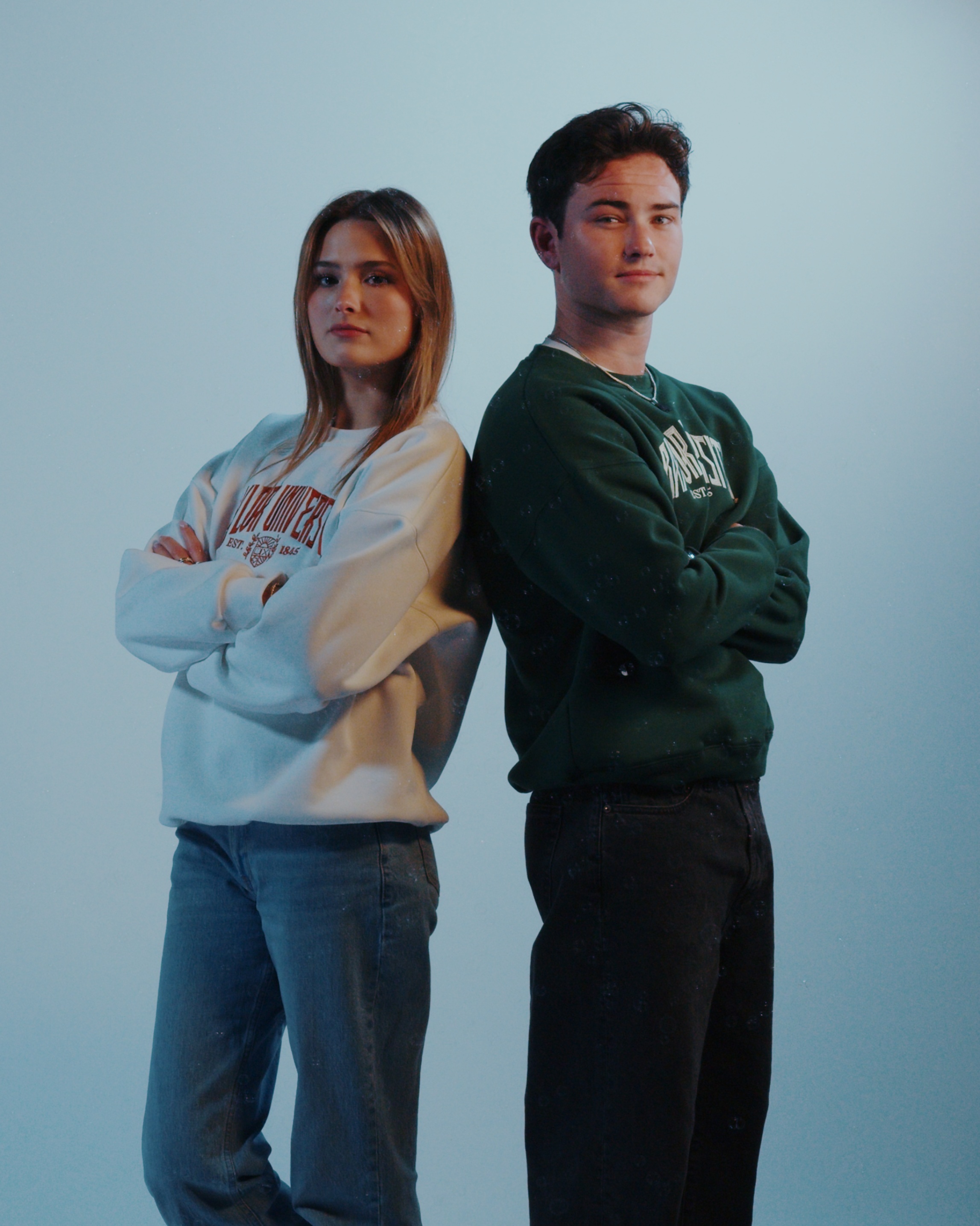 Two people standing side by side against a plain background wearing Baylor University sweatshirts