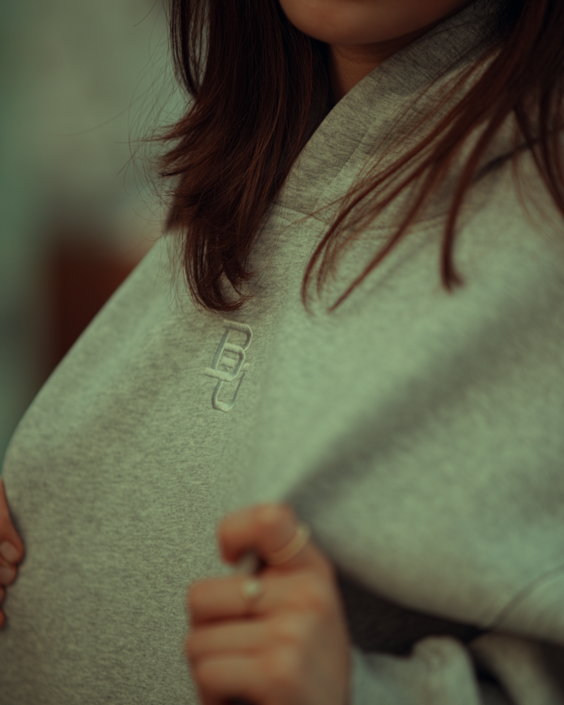 Close-up of a person wearing a light gray Baylor University hoodie with a brand logo on the chest.