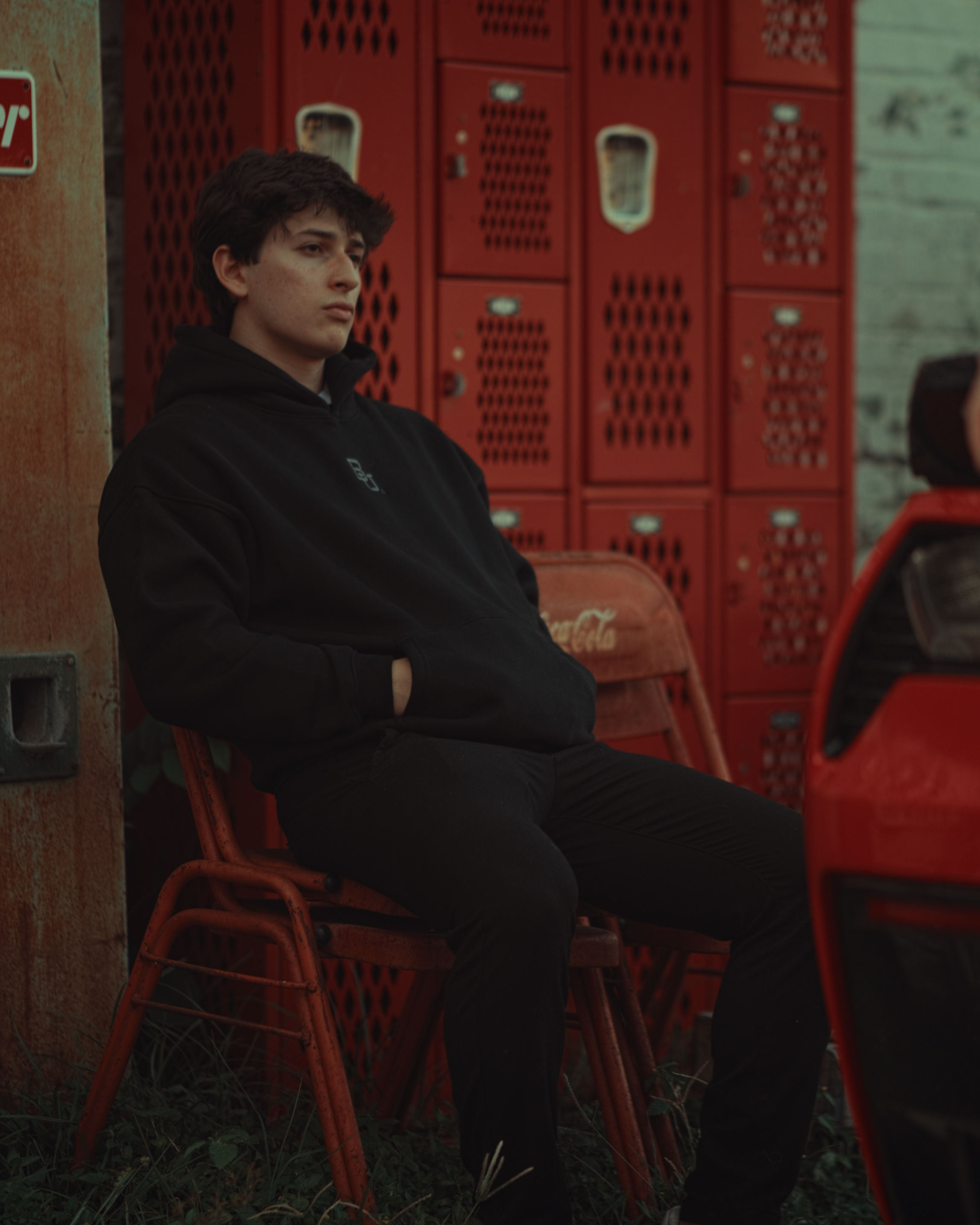 Man sitting on a red chair in front of stacked red crates wearing black Baylor hoodie