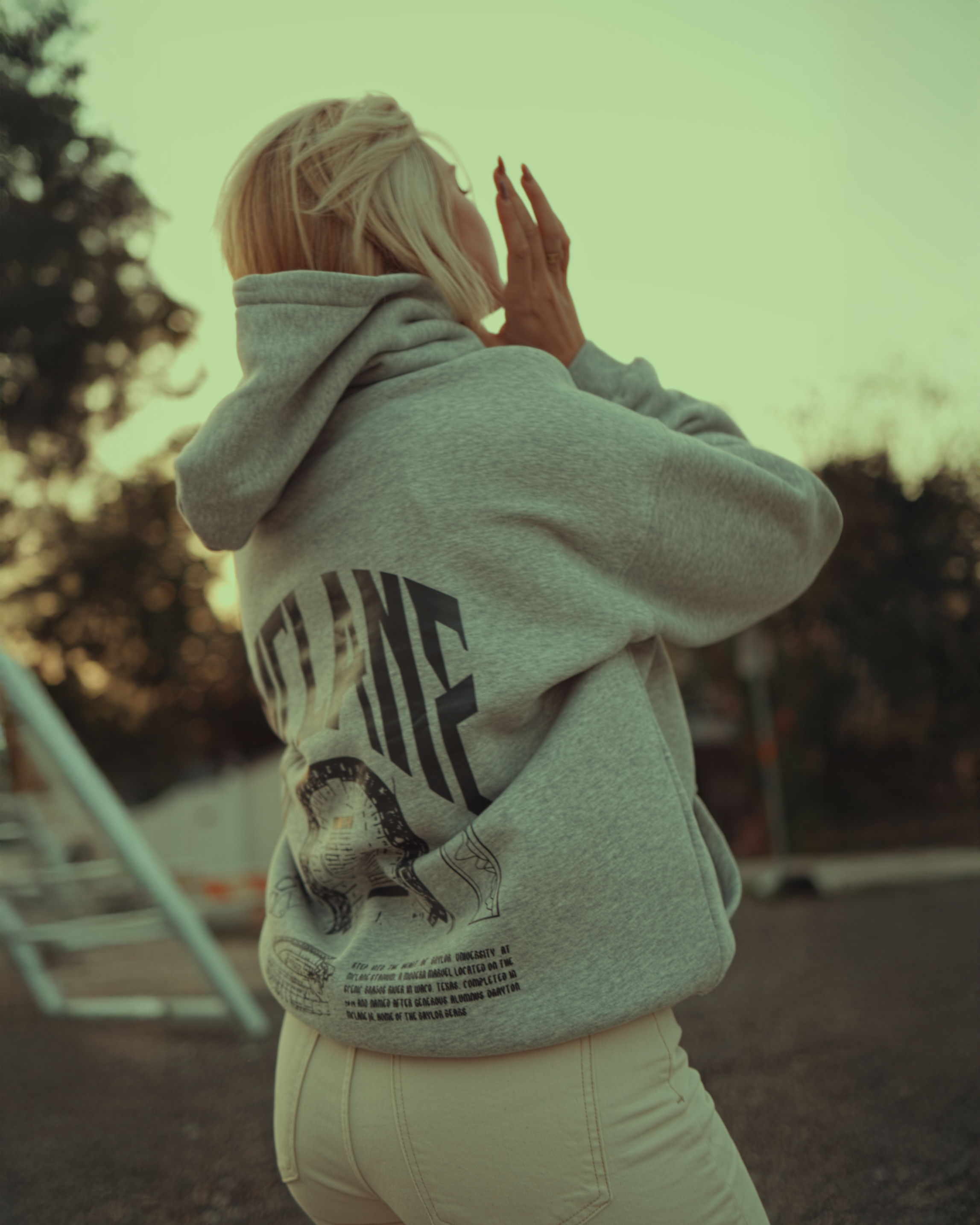 Person wearing a Baylor hoodie with text and graphics on the back, standing outdoors.