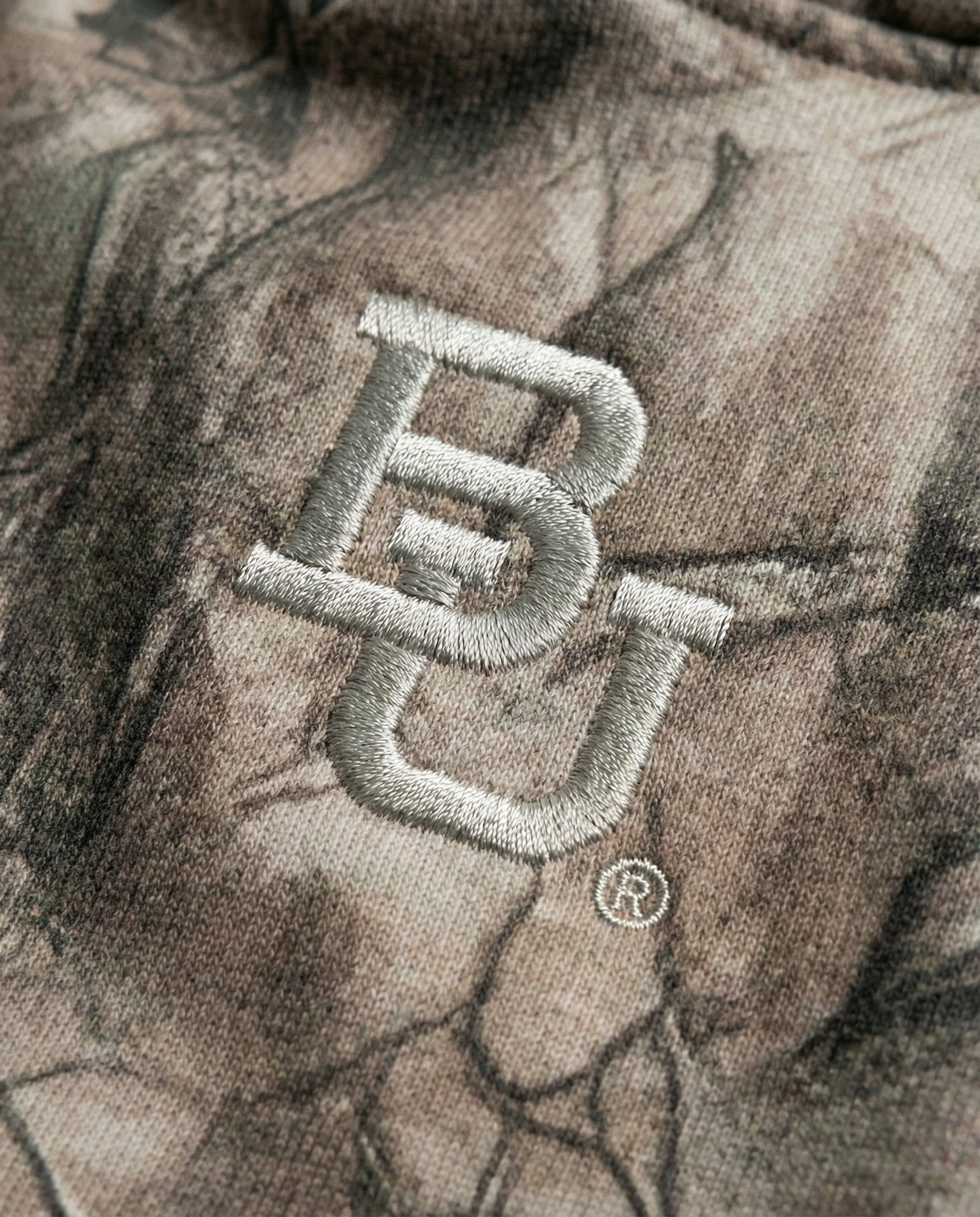 Close-up of a camouflage-patterned fabric with a the baylor university "BU" logo