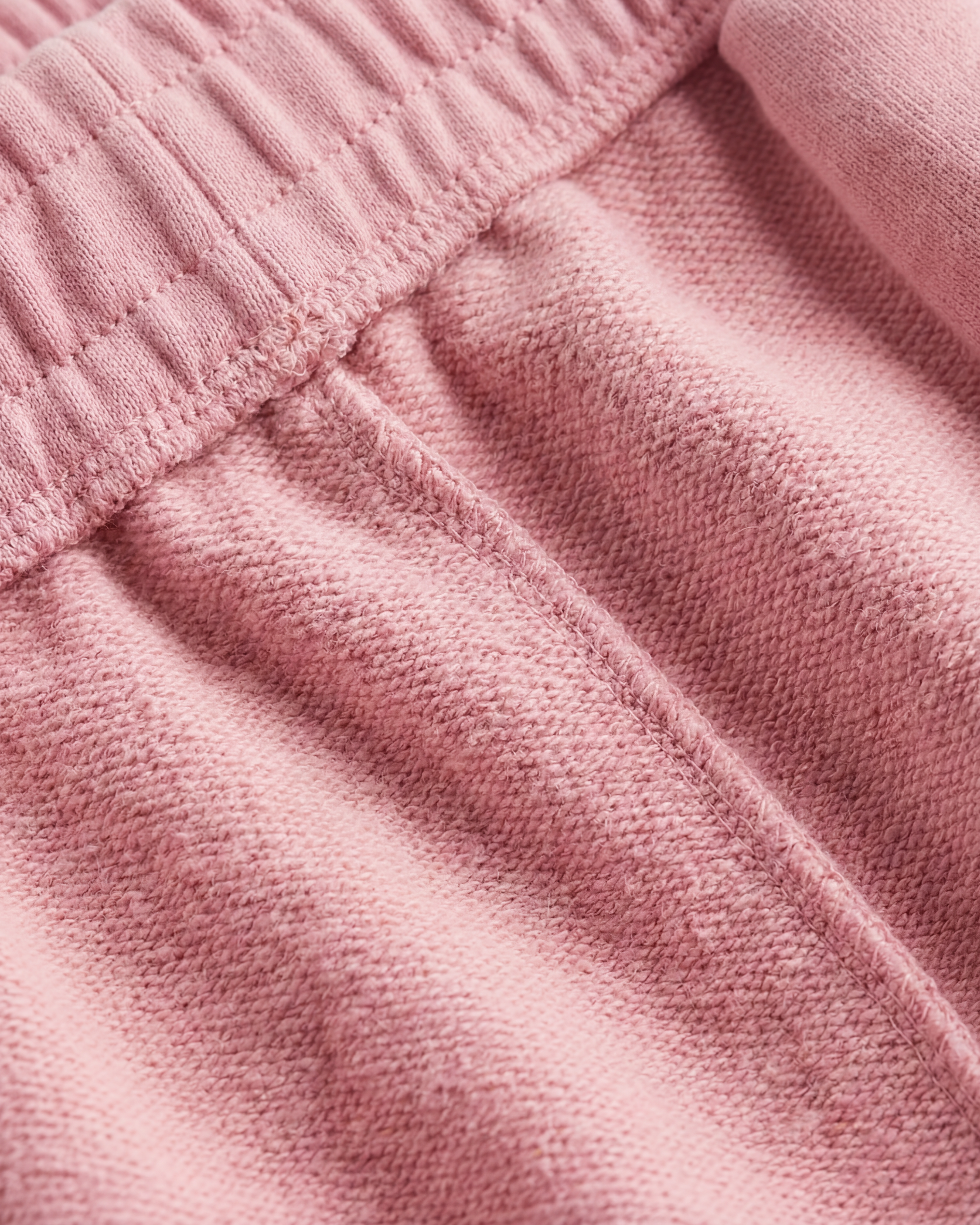 Model in pink wide-leg acid wash pants on light background