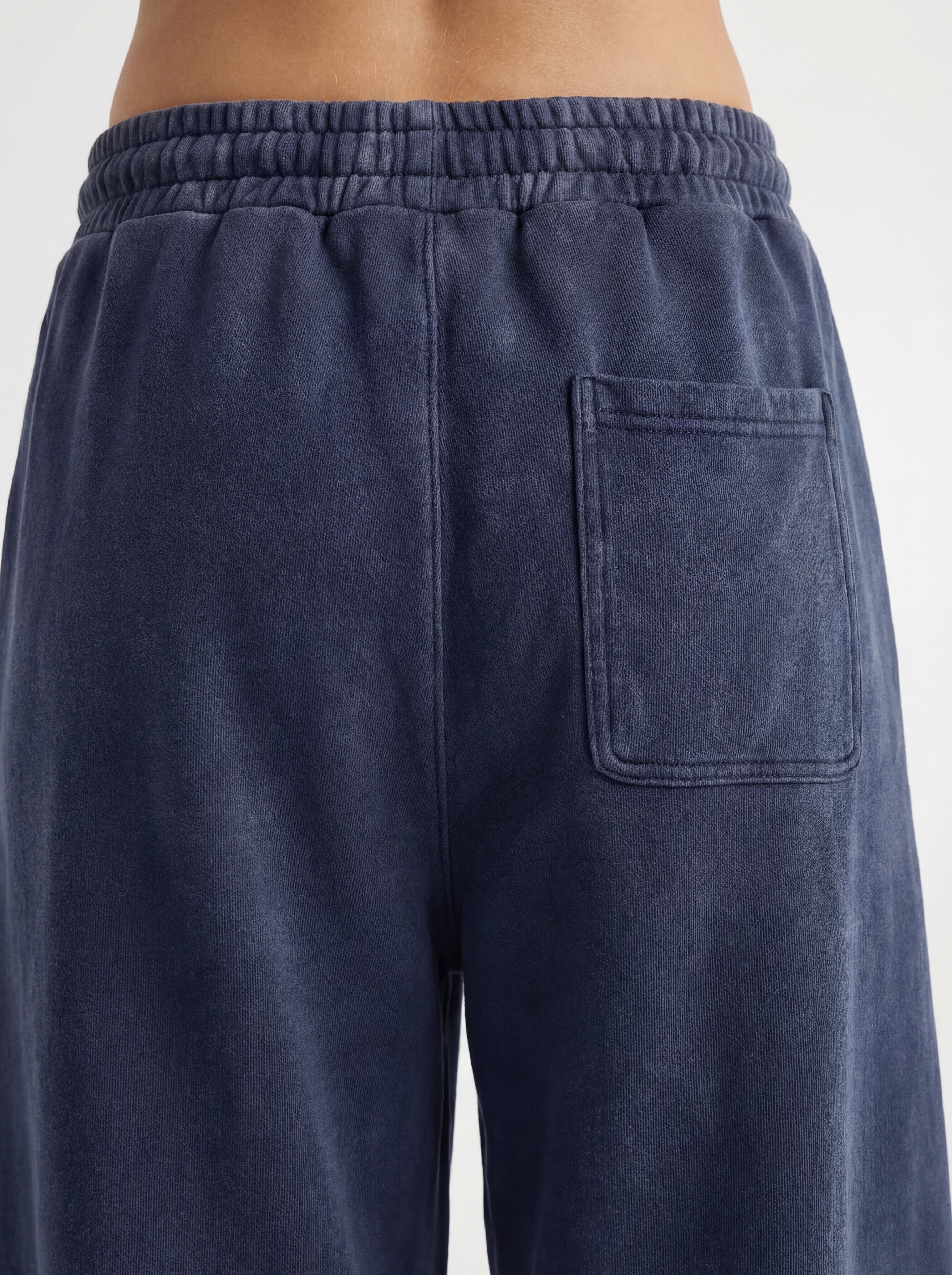 Navy blue sweatpants with a pocket on a light gray background