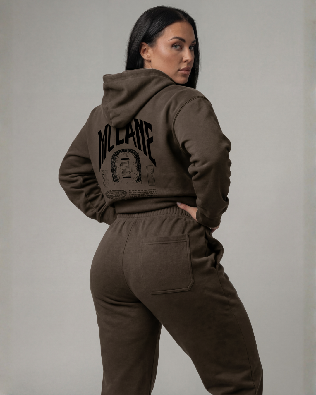 girl model wearing a brown baylor university hoodie and pants with 'MCLANE' branding on a gray background