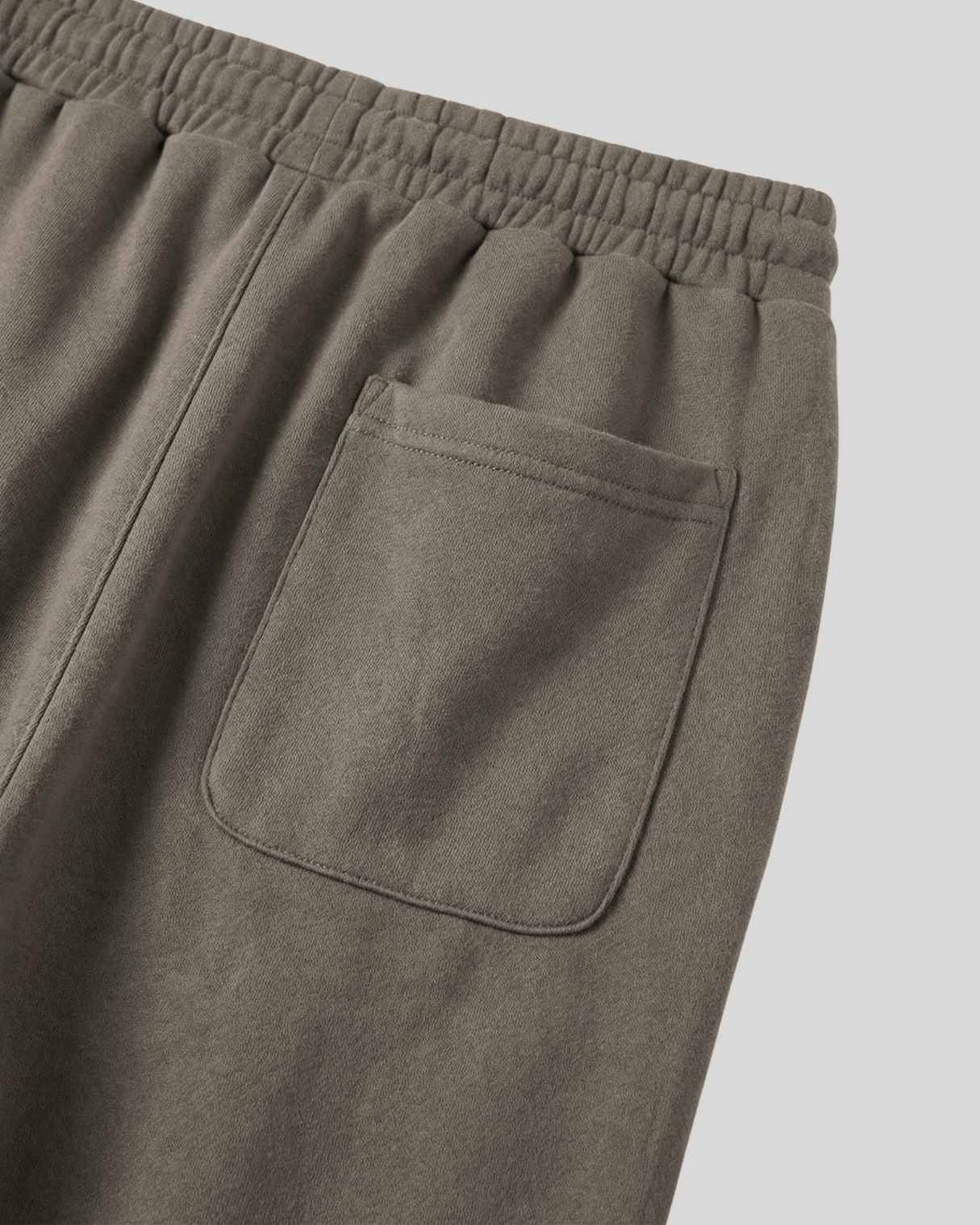 Close-up of the back of olive green sweatpants with a pocket on a white background