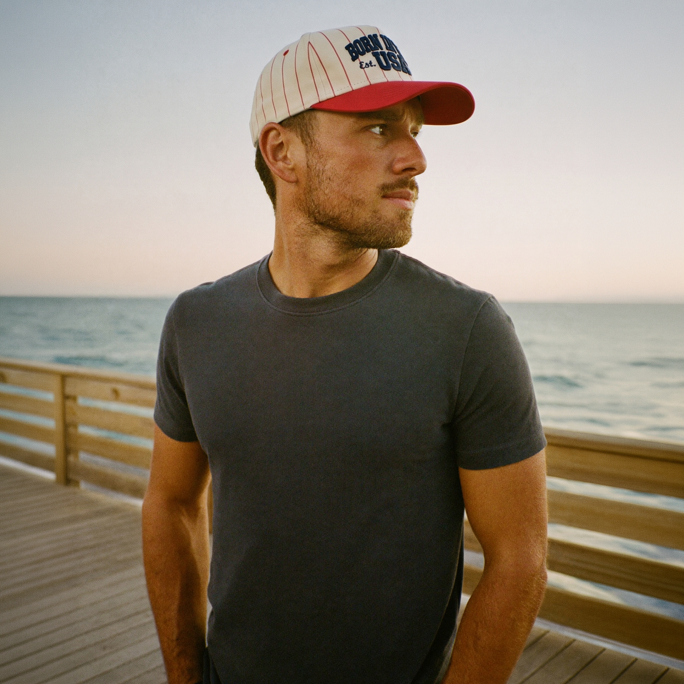 Man wearing a cap and t-shirt on a wooden pier by the ocean