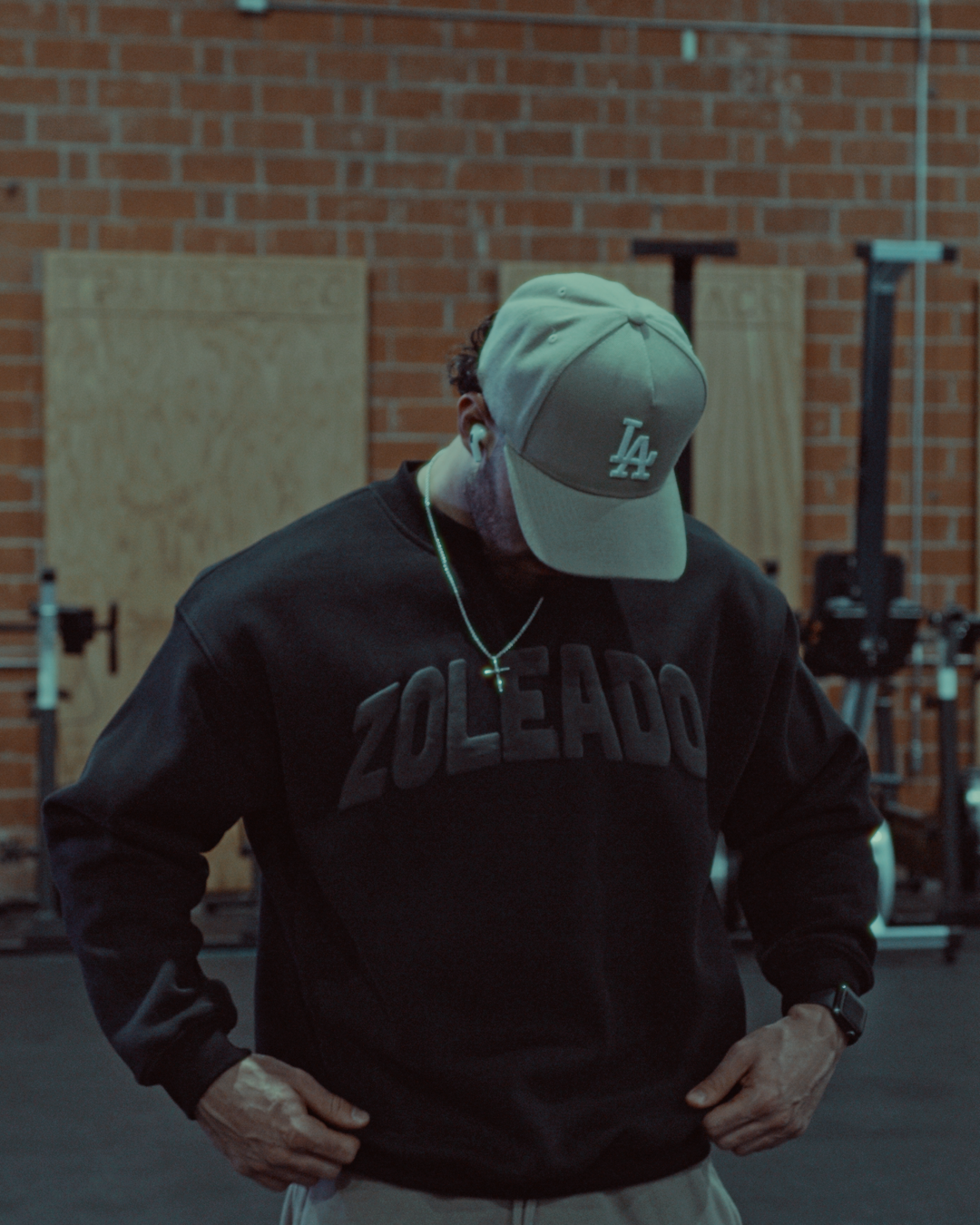 hot male model wearing an LA hat wearing a black zoleado puff print crewneck
