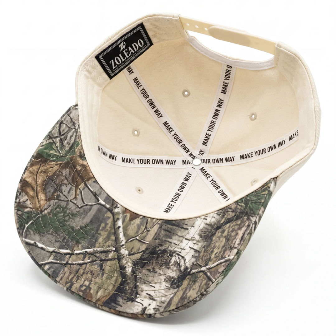 Texas camo Lone Star hat detail — close-up of brown 3D embroidered TEXAS lettering on cream twill