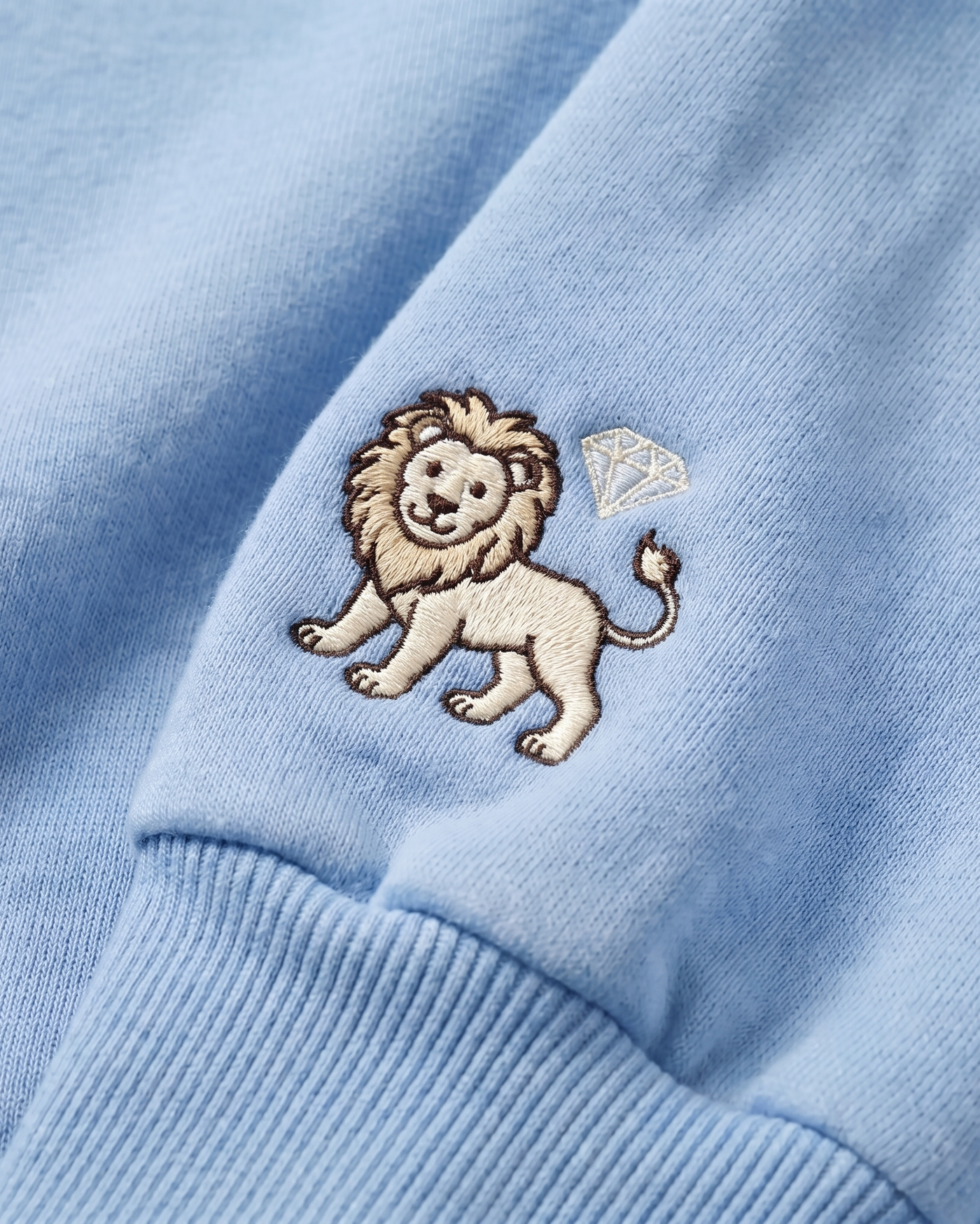 Embroidered lion with a diamond on a light blue fabric background