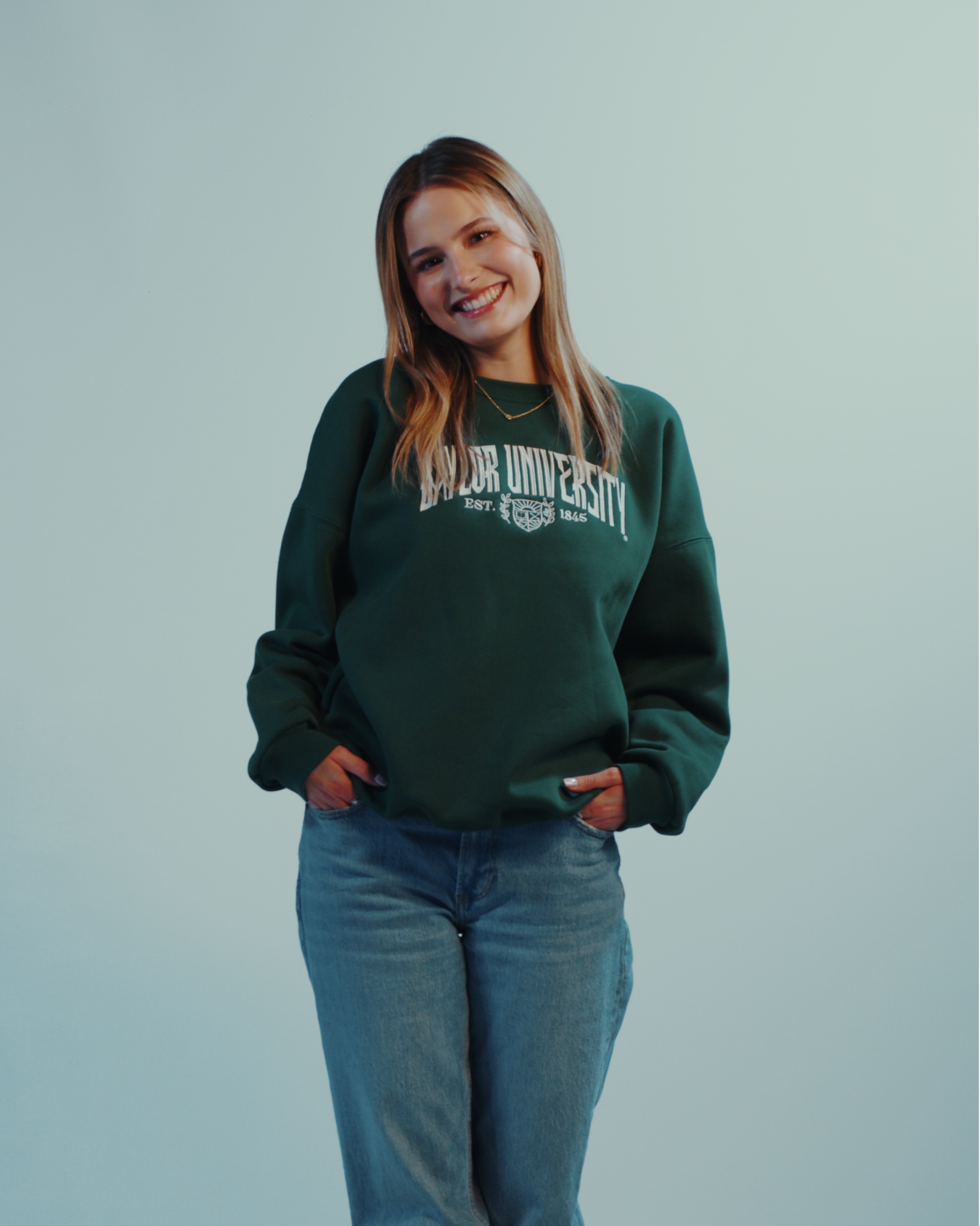 Hot girl wearing a green embroidered Baylor University embroidered sweatshirt crewneck on a white background