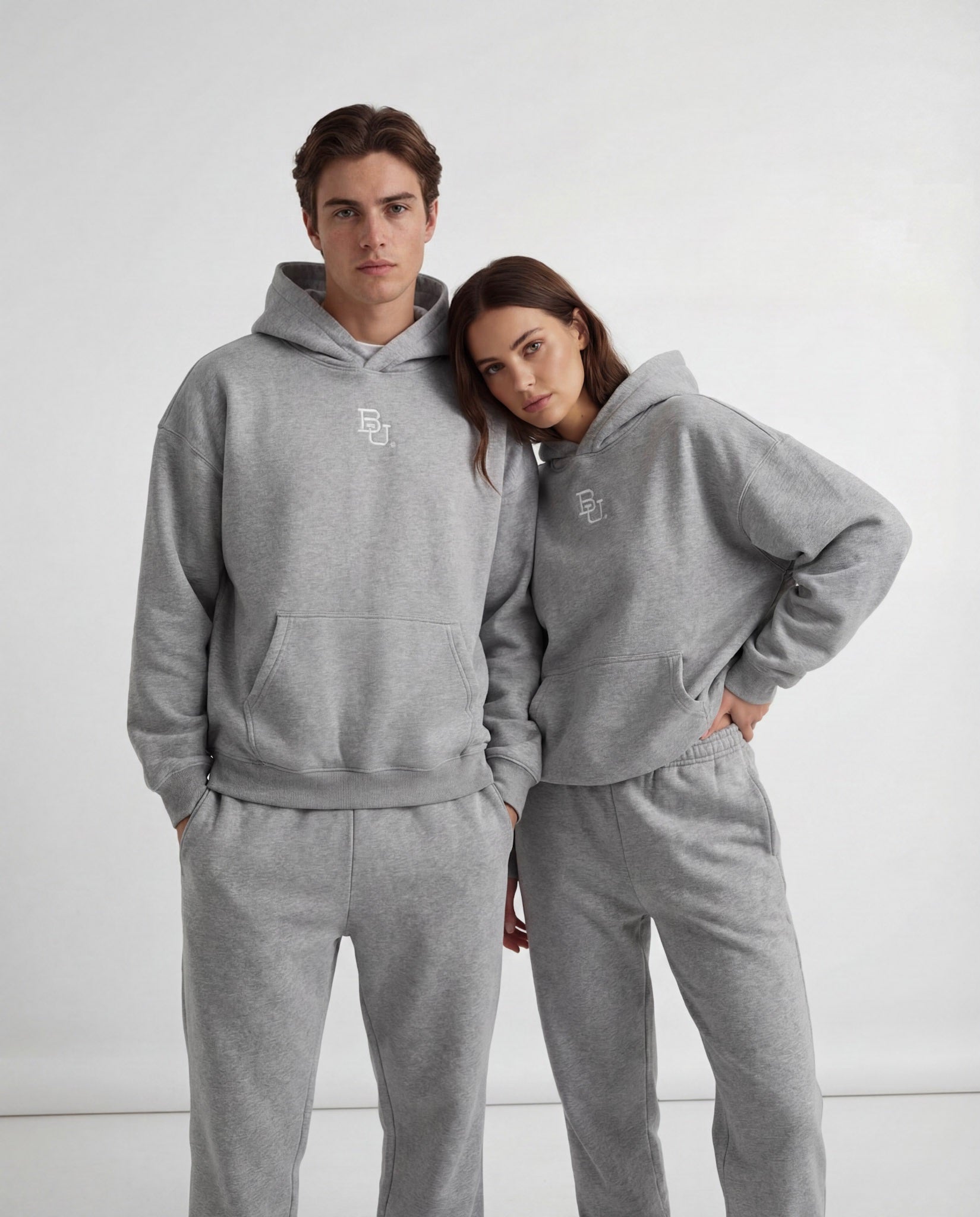 Two people wearing matching gray Baylor University McLane hoodies and pants against a white background