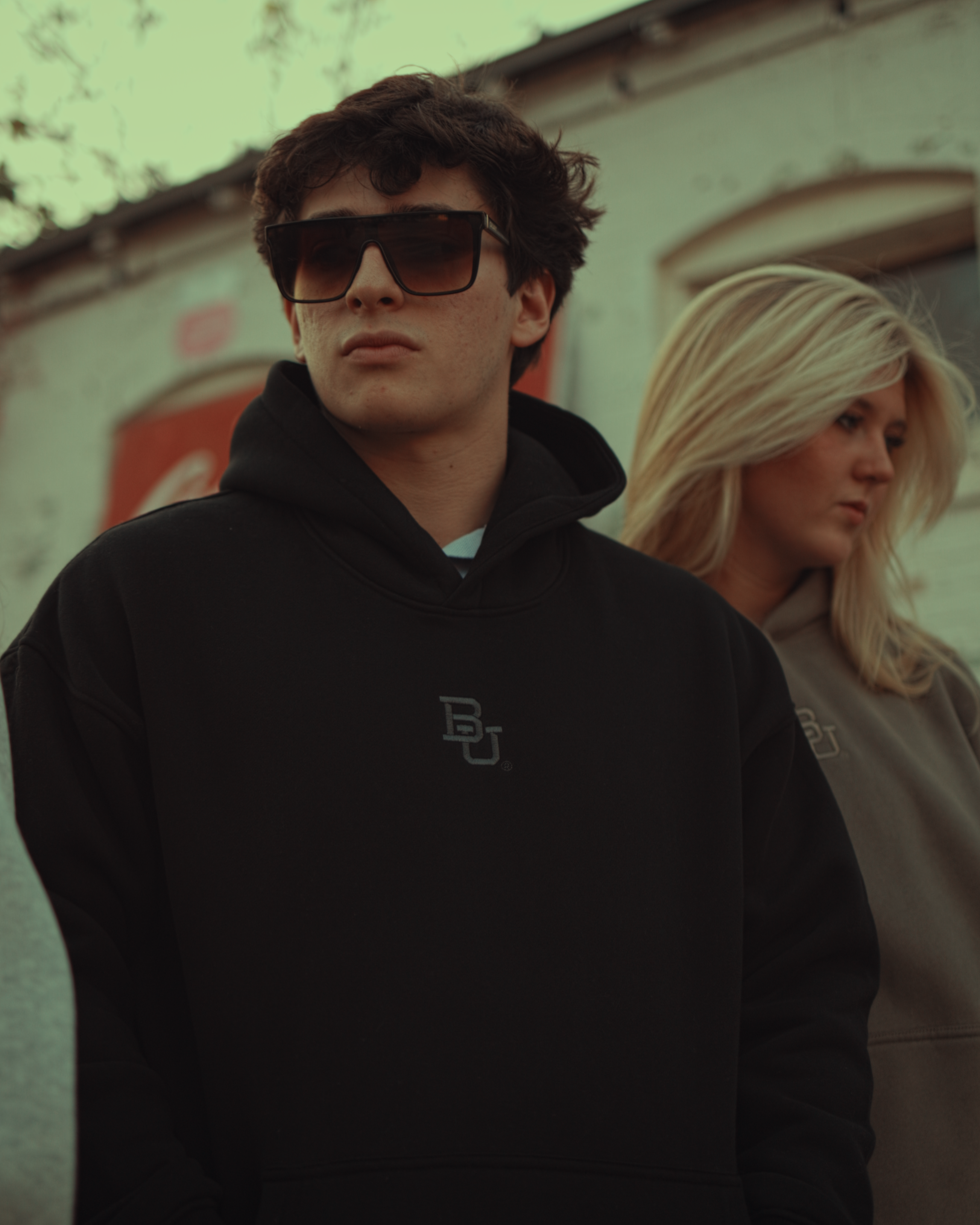 Two people wearing baylor university hoodies with a logo, standing outdoors.