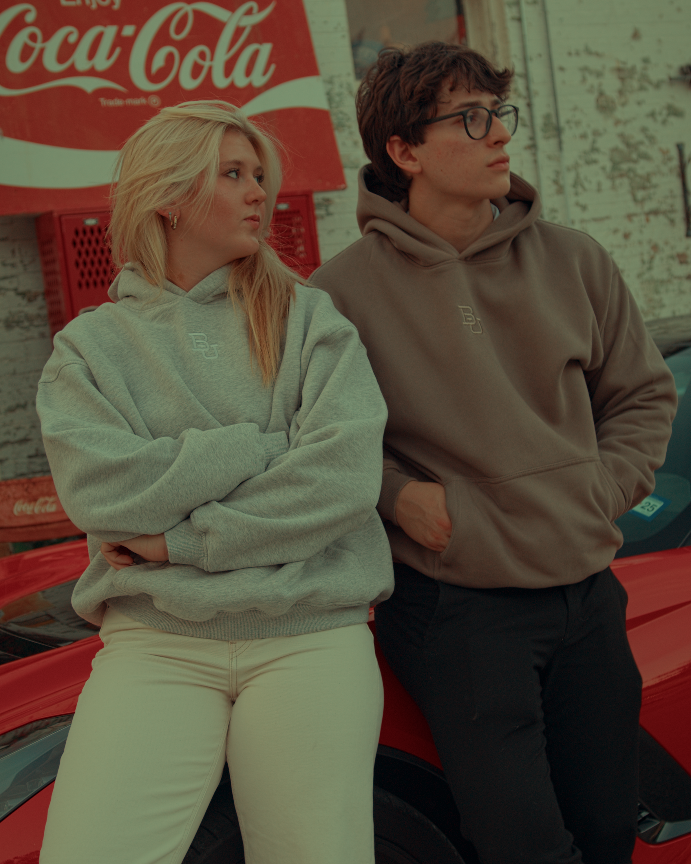 Two people standing in front of a Coca-Cola truck wearing Baylor University hoodies