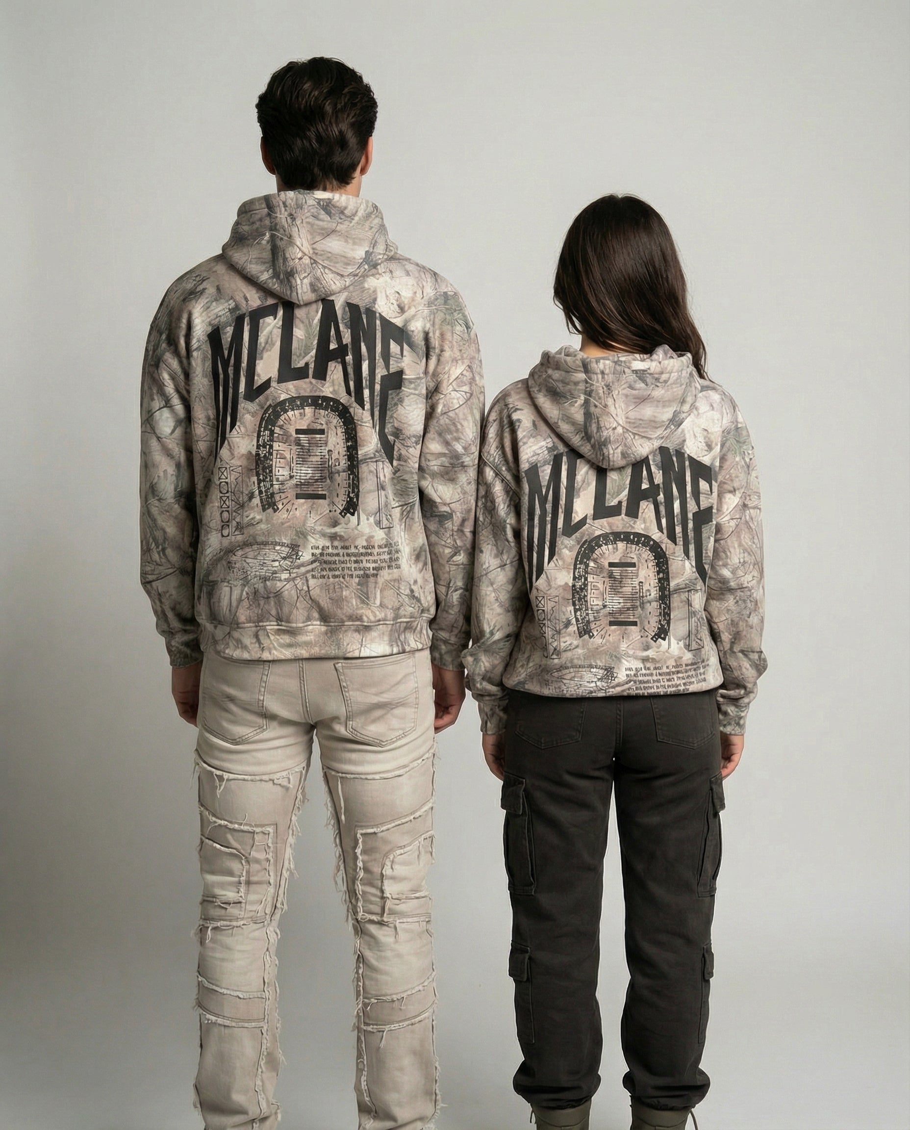Two people wearing camouflage hoodies with 'MCLANE' branding on a plain background