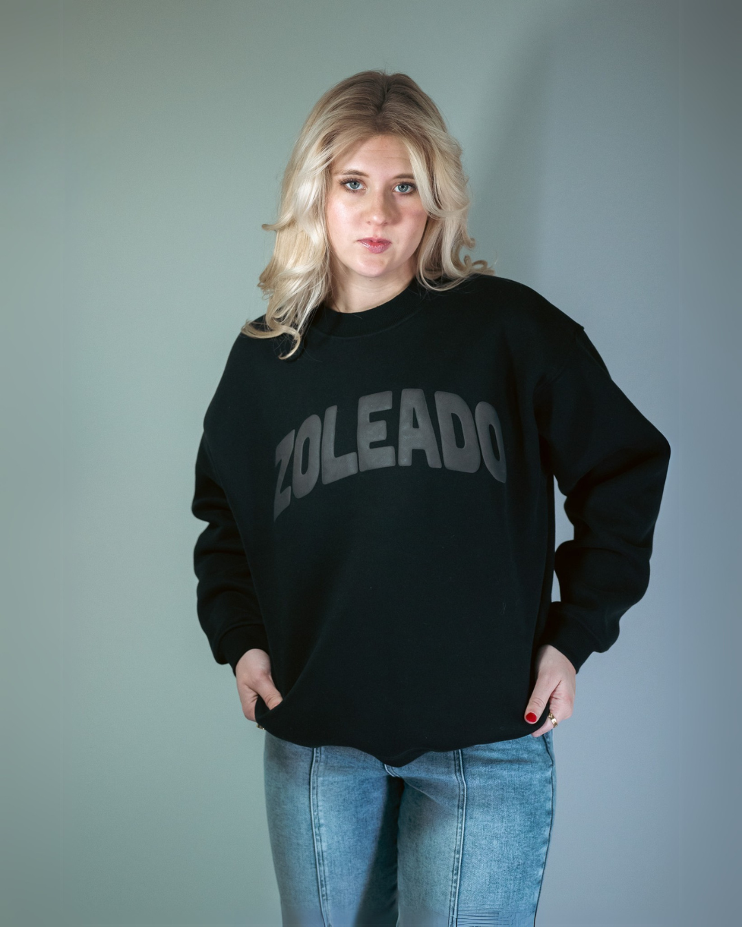 blonde model wearing a black 'ZOLEADO' puff print crewneck sweatshirt