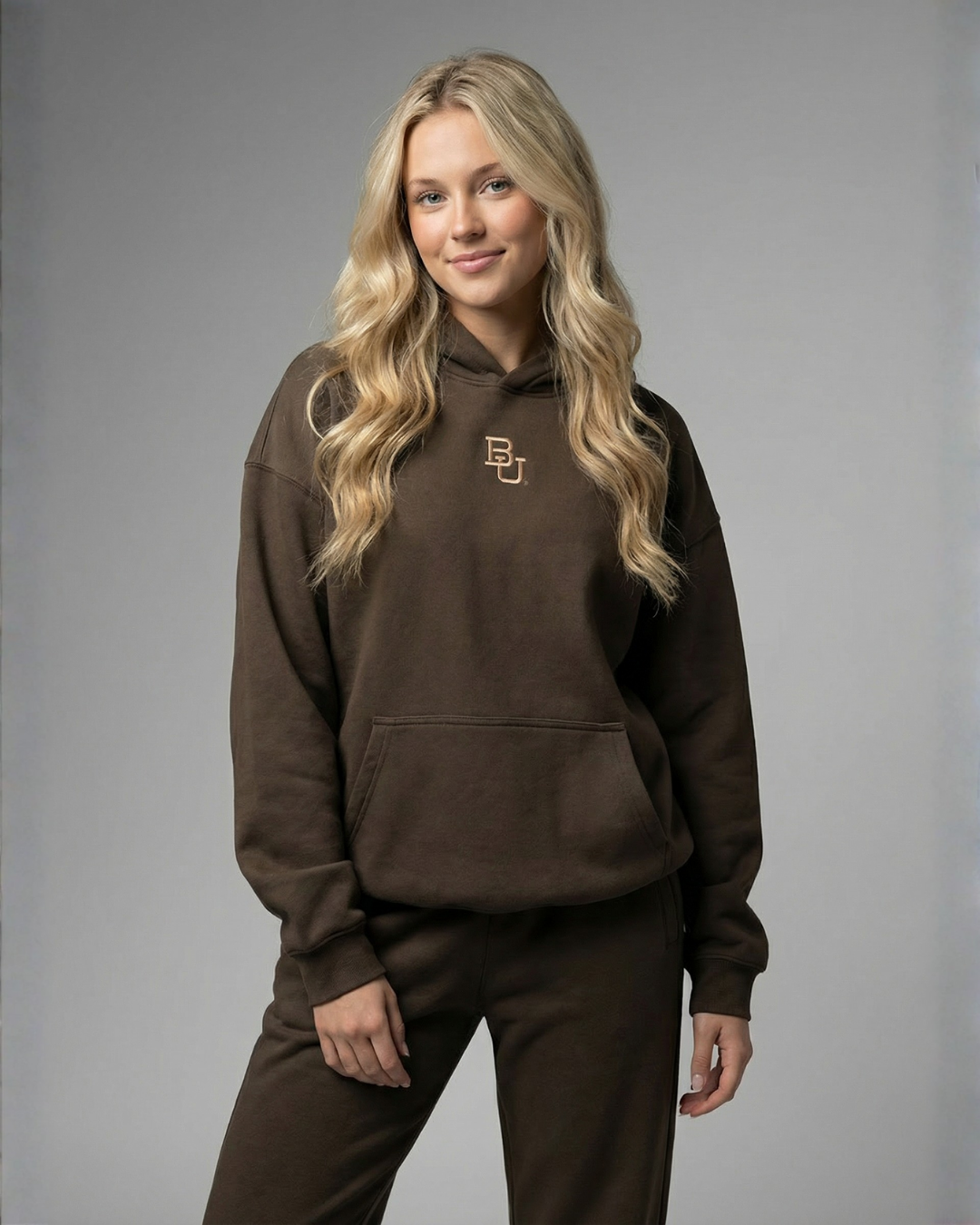 Woman wearing a brown hoodie with a logo on a gray background