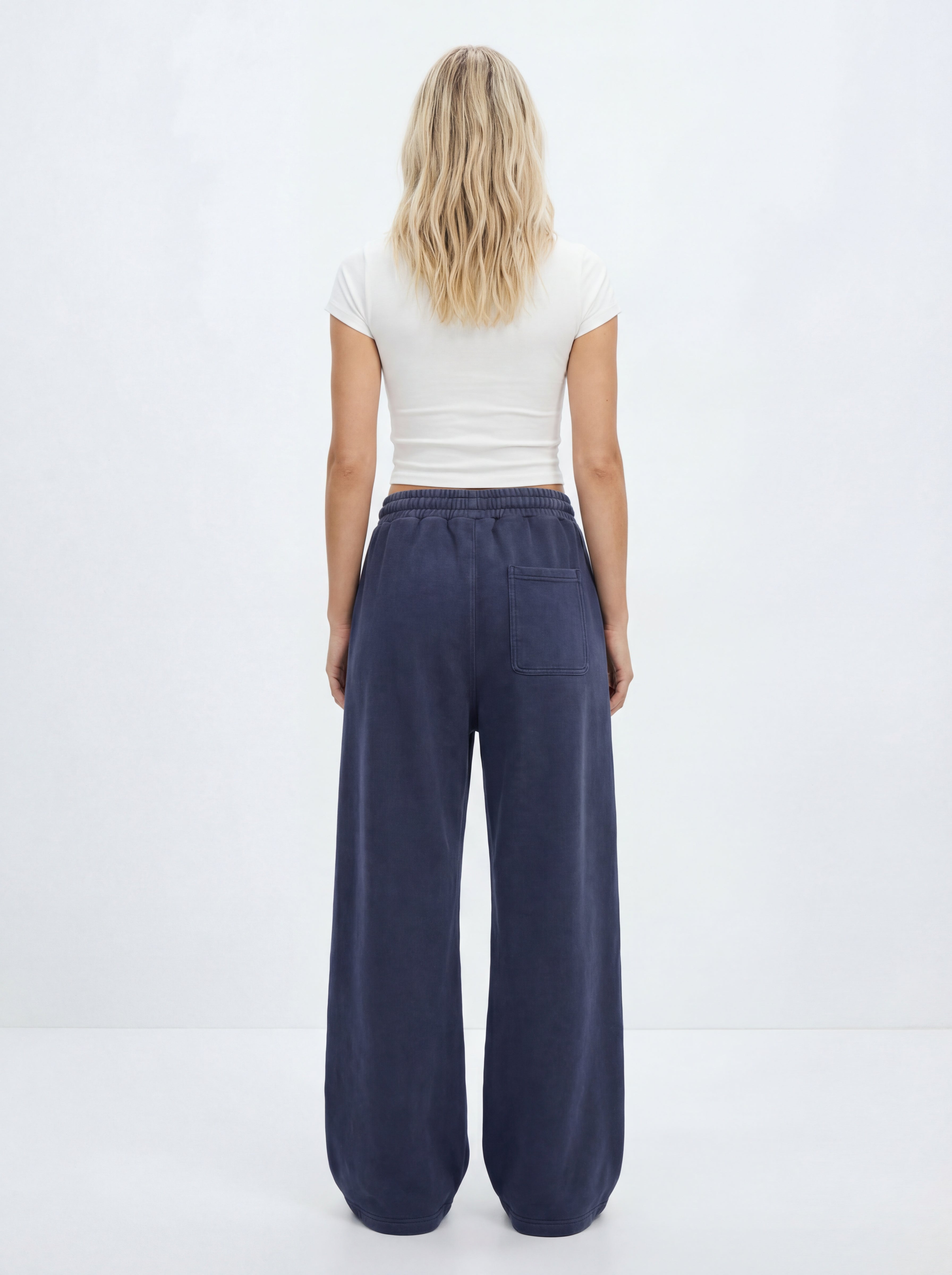 Person wearing navy wide-leg pants and a white top on a white background