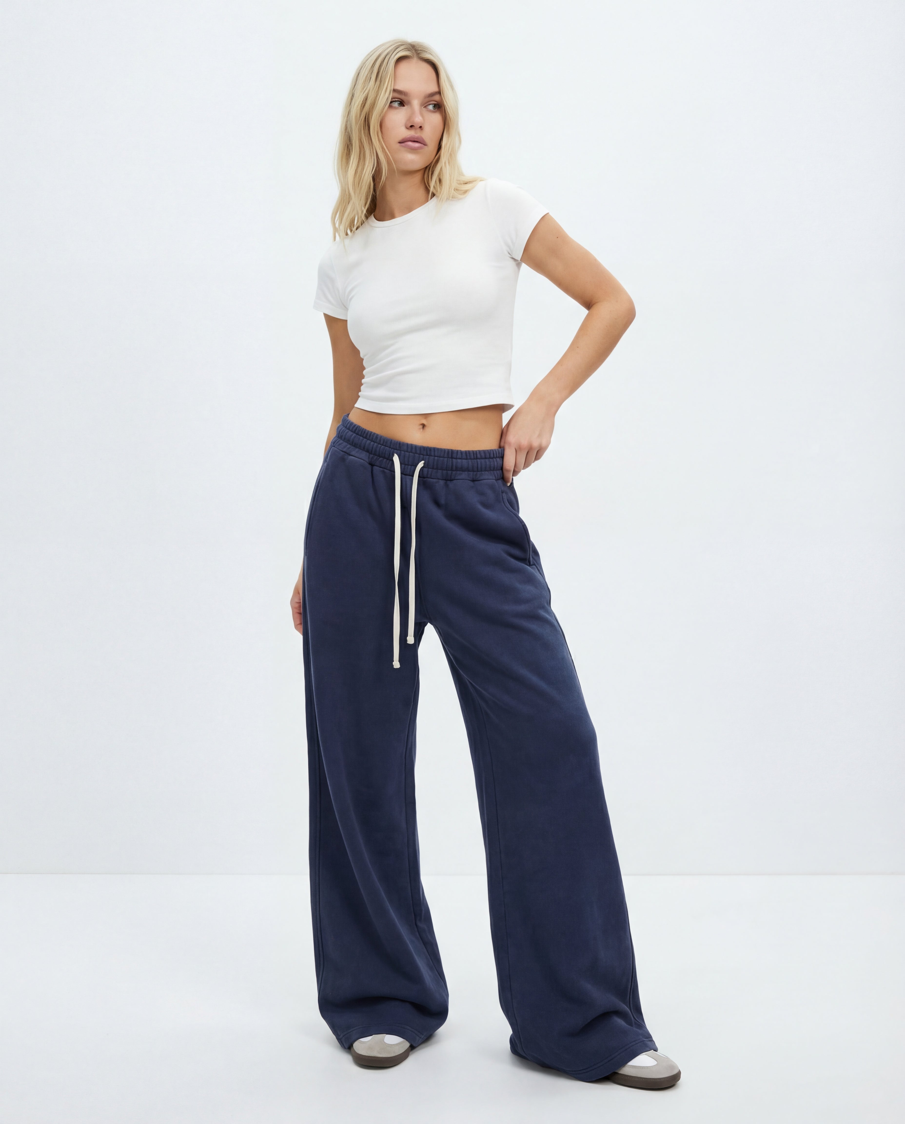 Woman wearing a white crop top and navy wide-leg pants on a white background