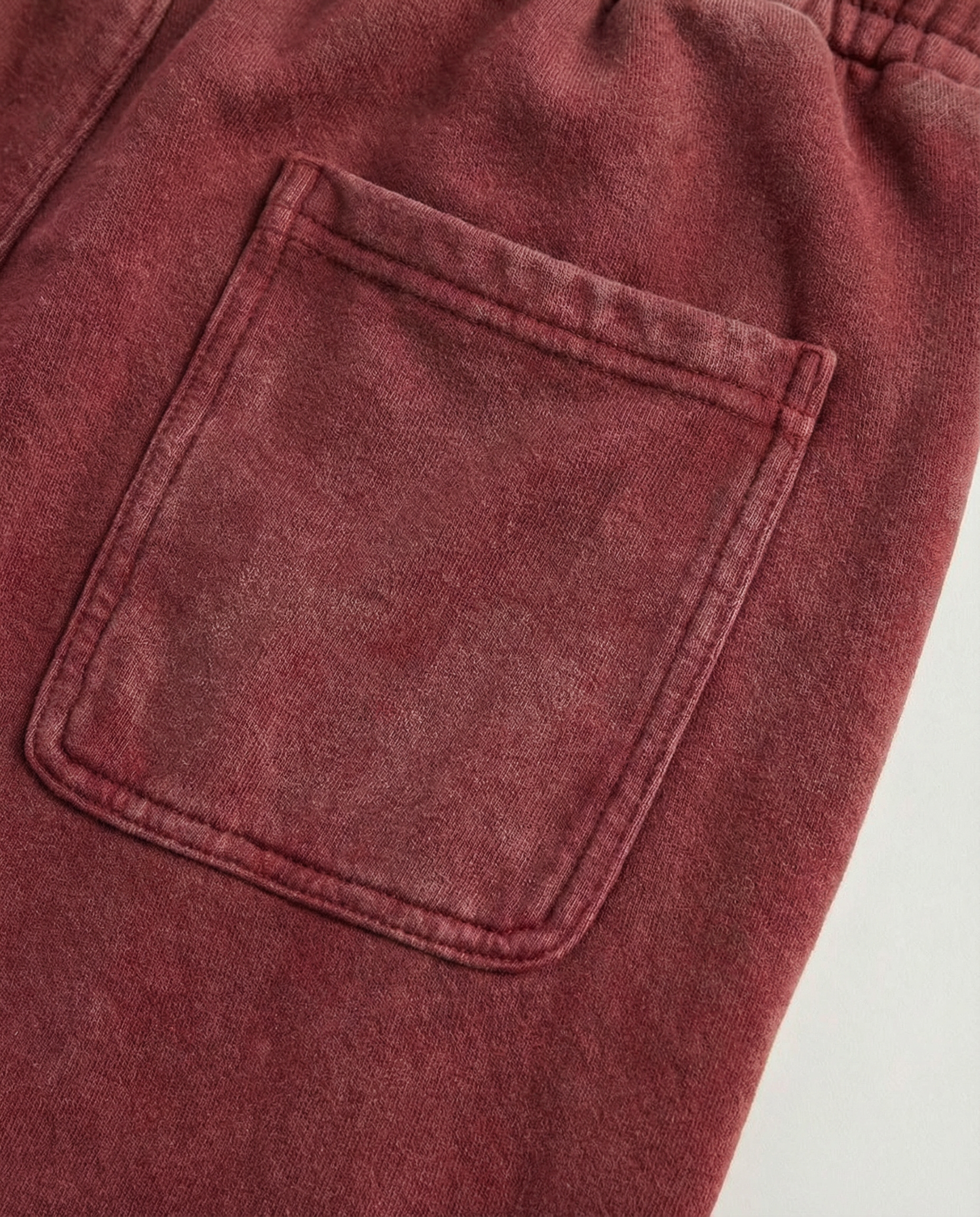 Close-up of a red sweatpants pocket on a plain background