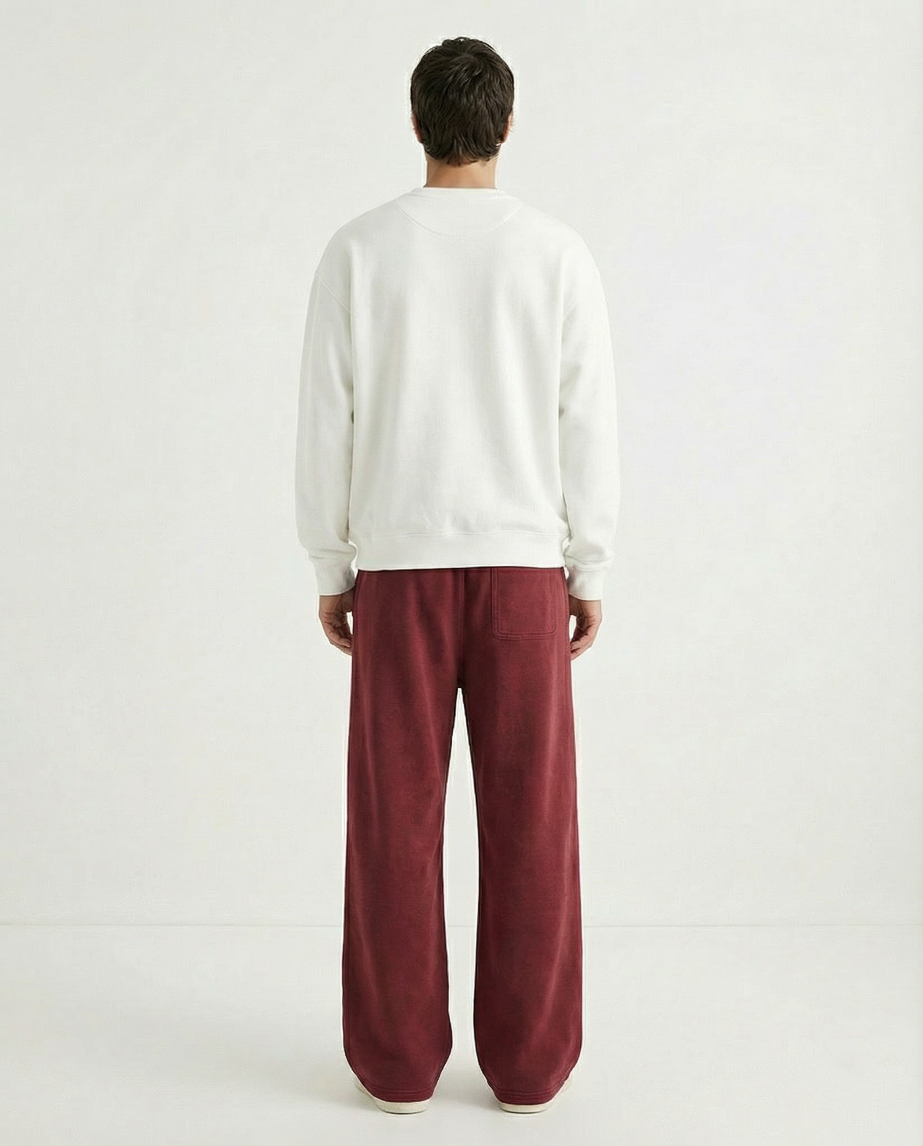 Person wearing a white sweater and red pants on a plain background