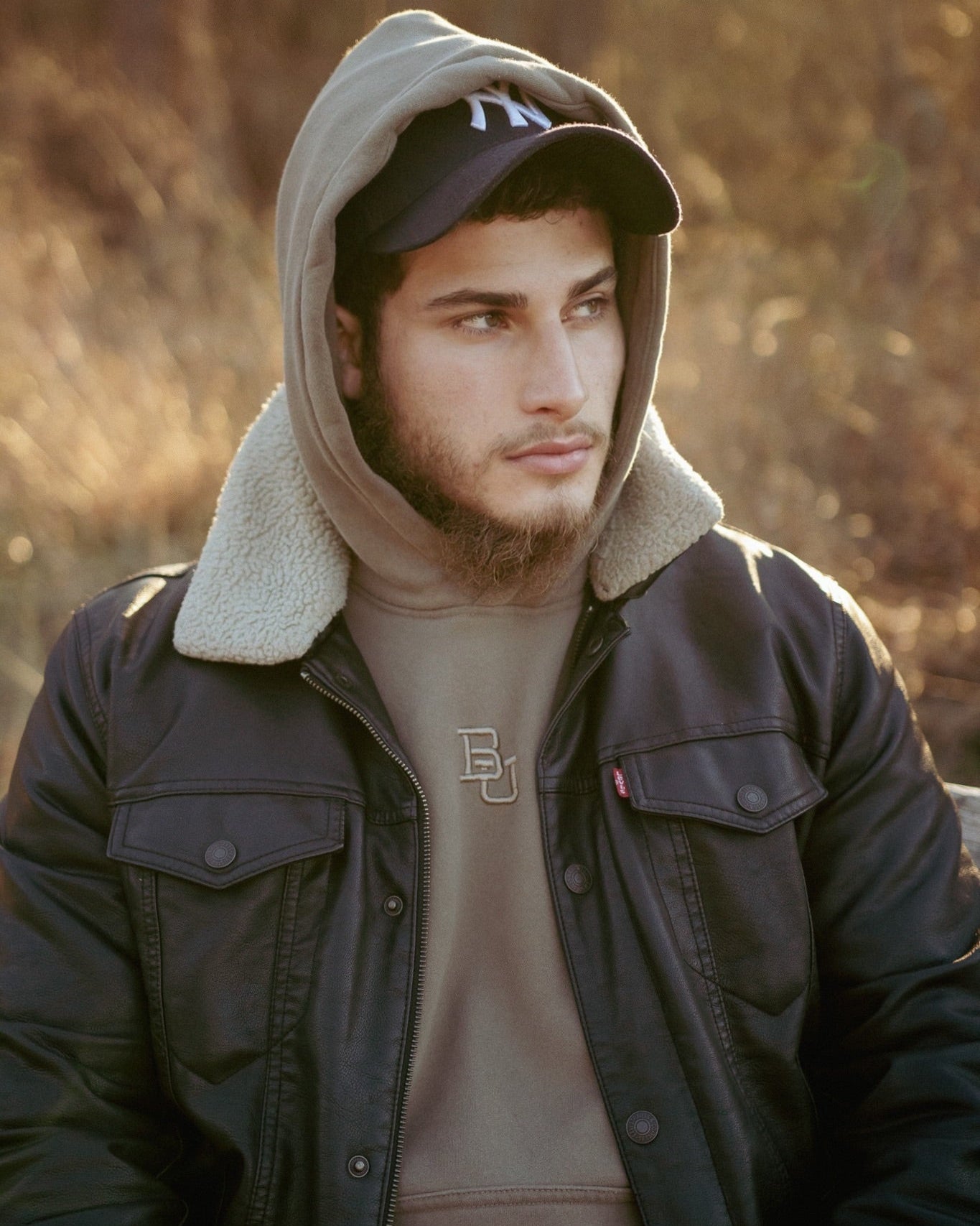 Male model wearing the Baylor University mclane stadium hoodie with a leather jacket and a new york hat