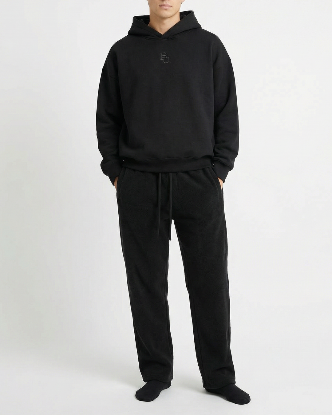 man wearing a black hoodie and pants set on a white background