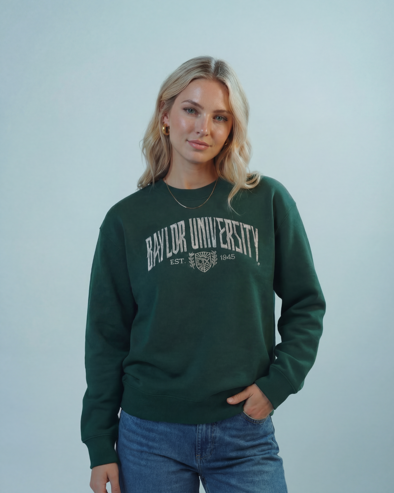blonde girl wearing a forrest green Baylor University sweatshirt against a plain background