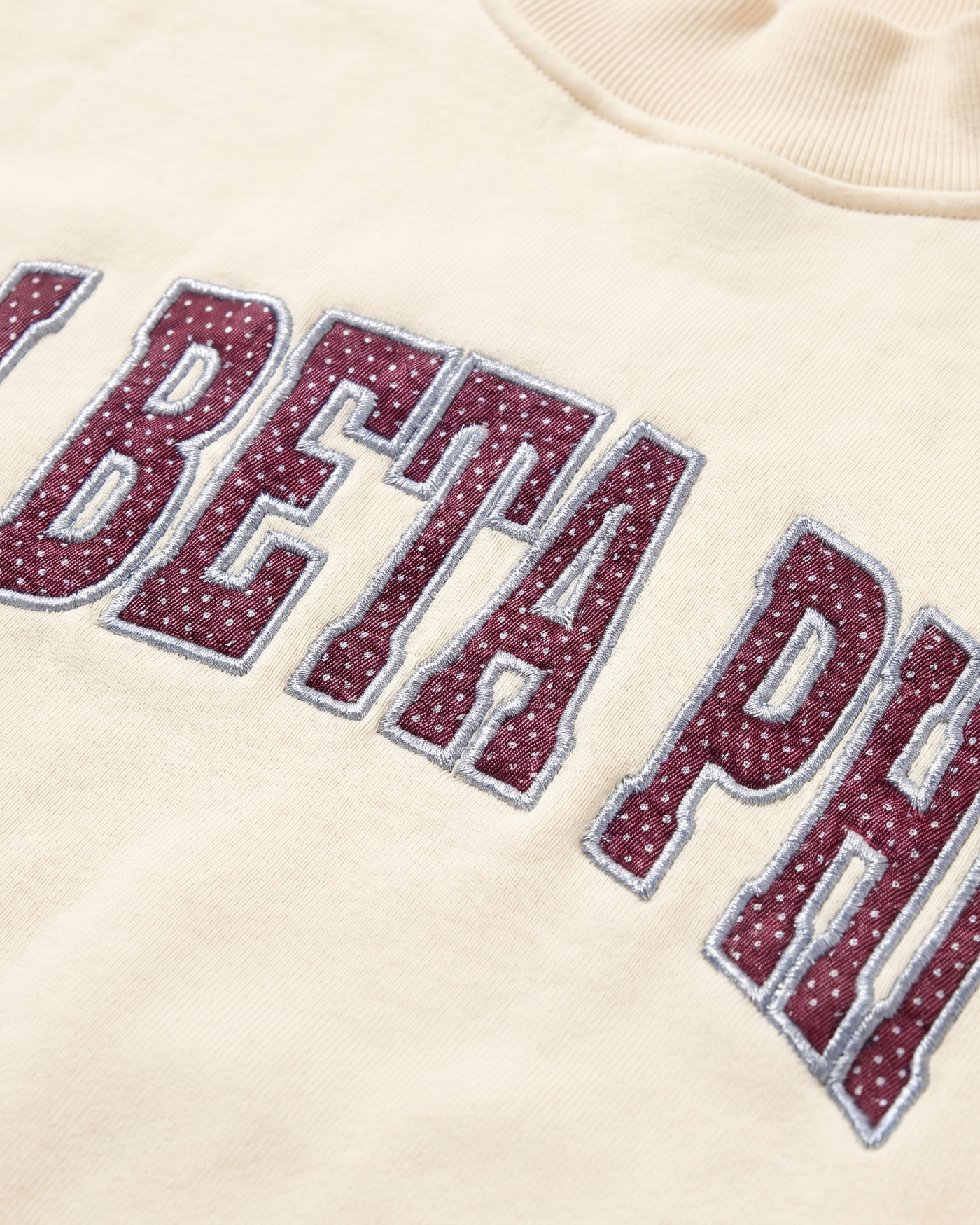 Pi Beta Phi chest patch embroidery close-up - wine polka-dot tackle-twill with silver-blue detail on cream