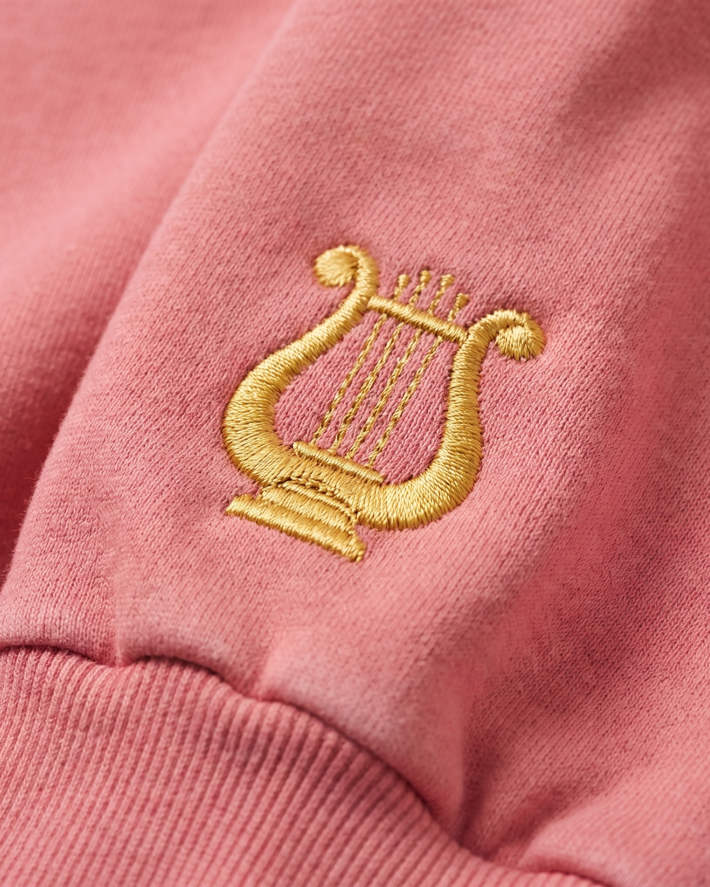 Alpha Chi Omega sleeve charm close-up - embroidered gold lyre on raspberry rose fleece