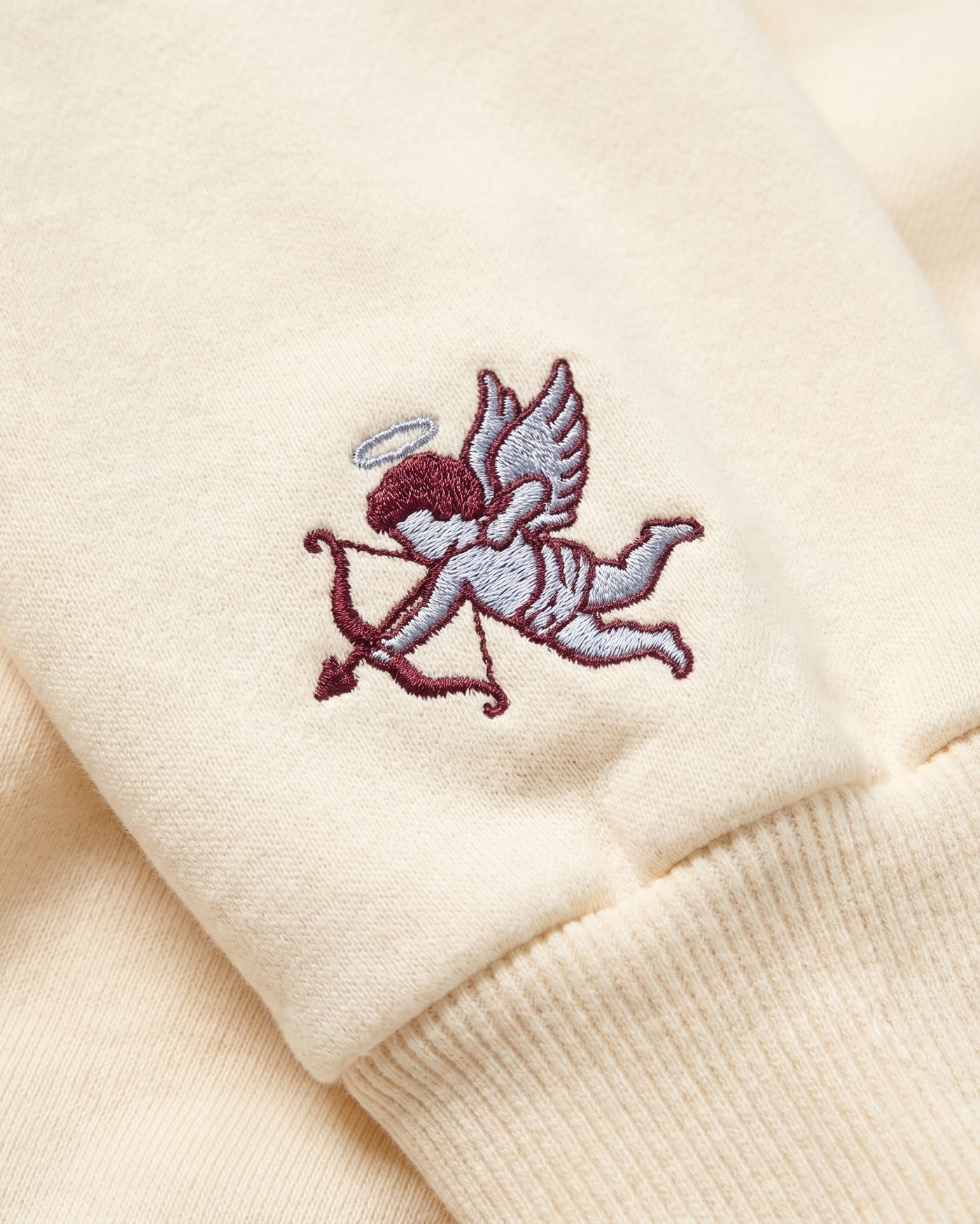 Pi Beta Phi sleeve charm close-up - embroidered angel and arrow on cream fleece