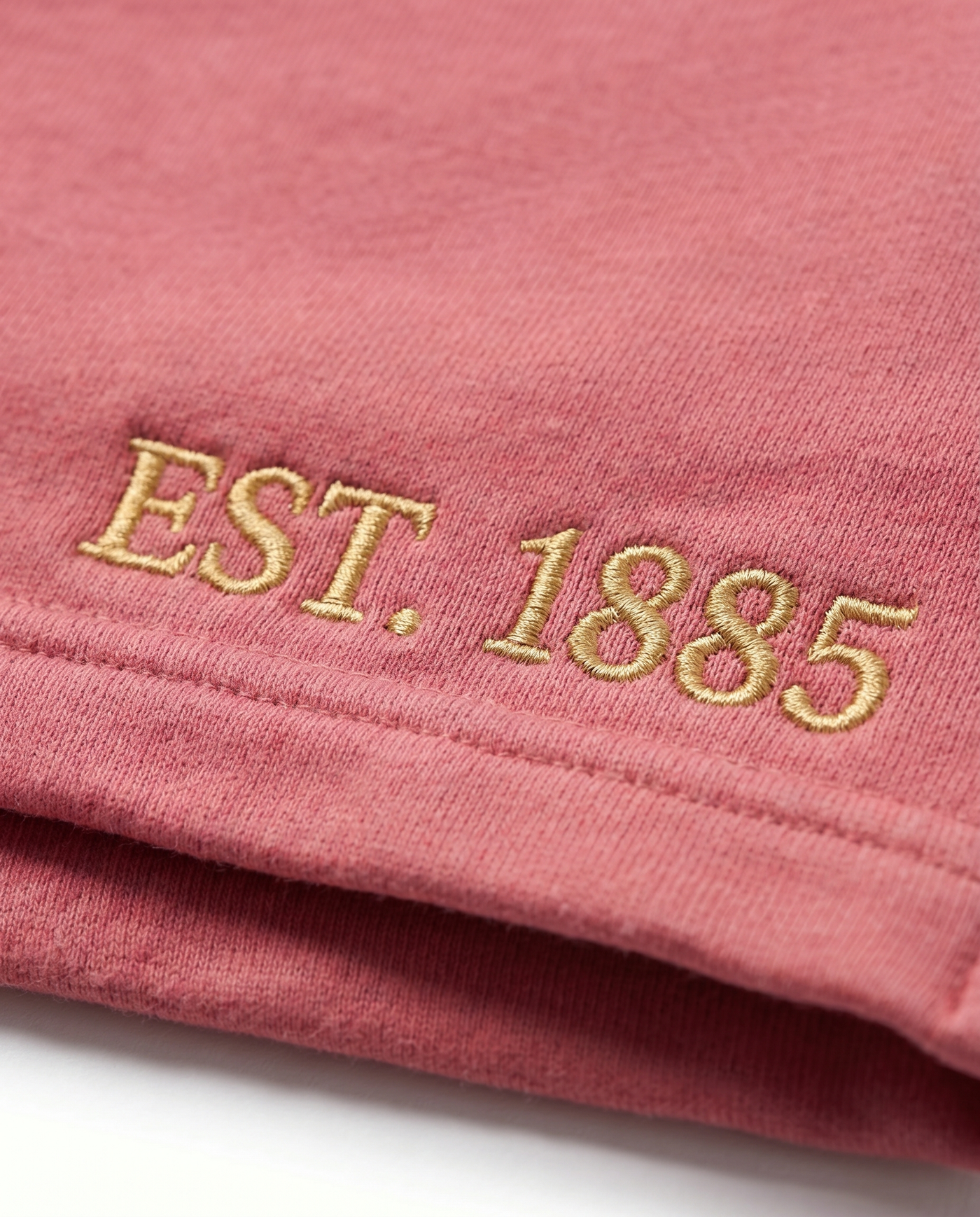Alpha Chi Omega Shorts EST. 1885 leg embroidery close-up in gold on raspberry rose cotton fleece