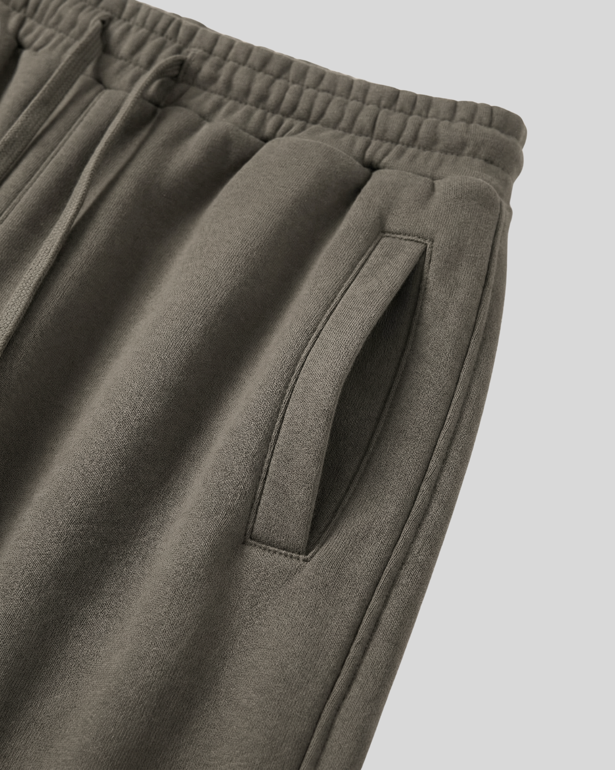 Close-up of olive green sweatpants with a pocket on a white background