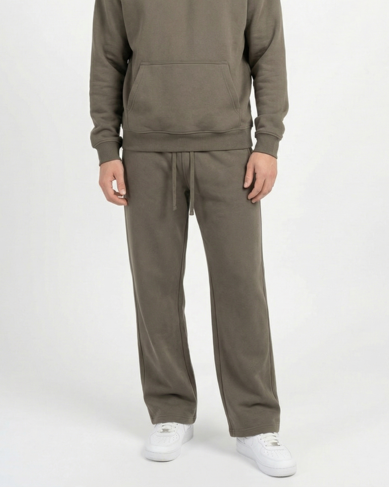 Person wearing an olive green tracksuit with white shoes on a white background